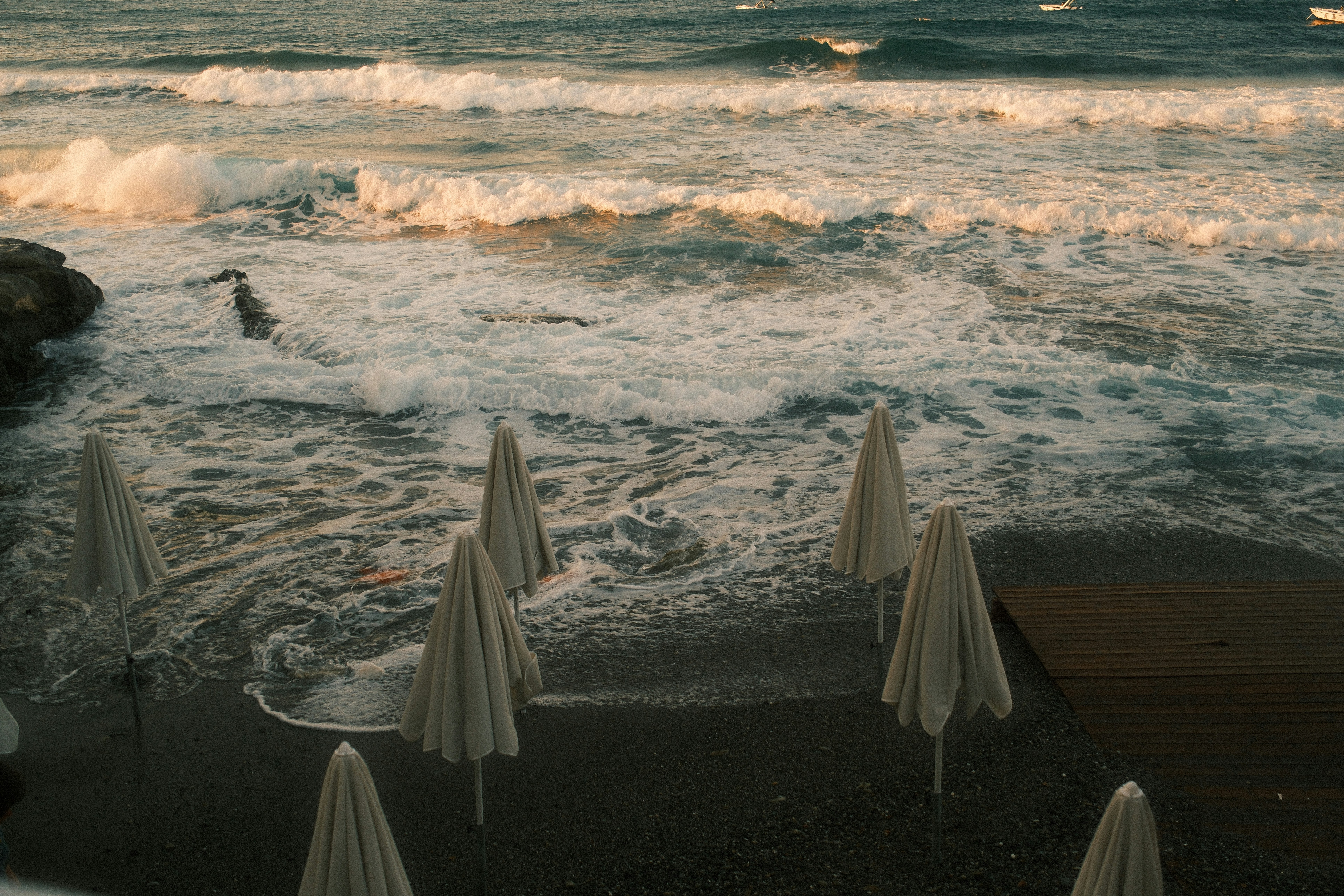 Closed beach umbrellas on dark sand - Free Photo on Unsplash