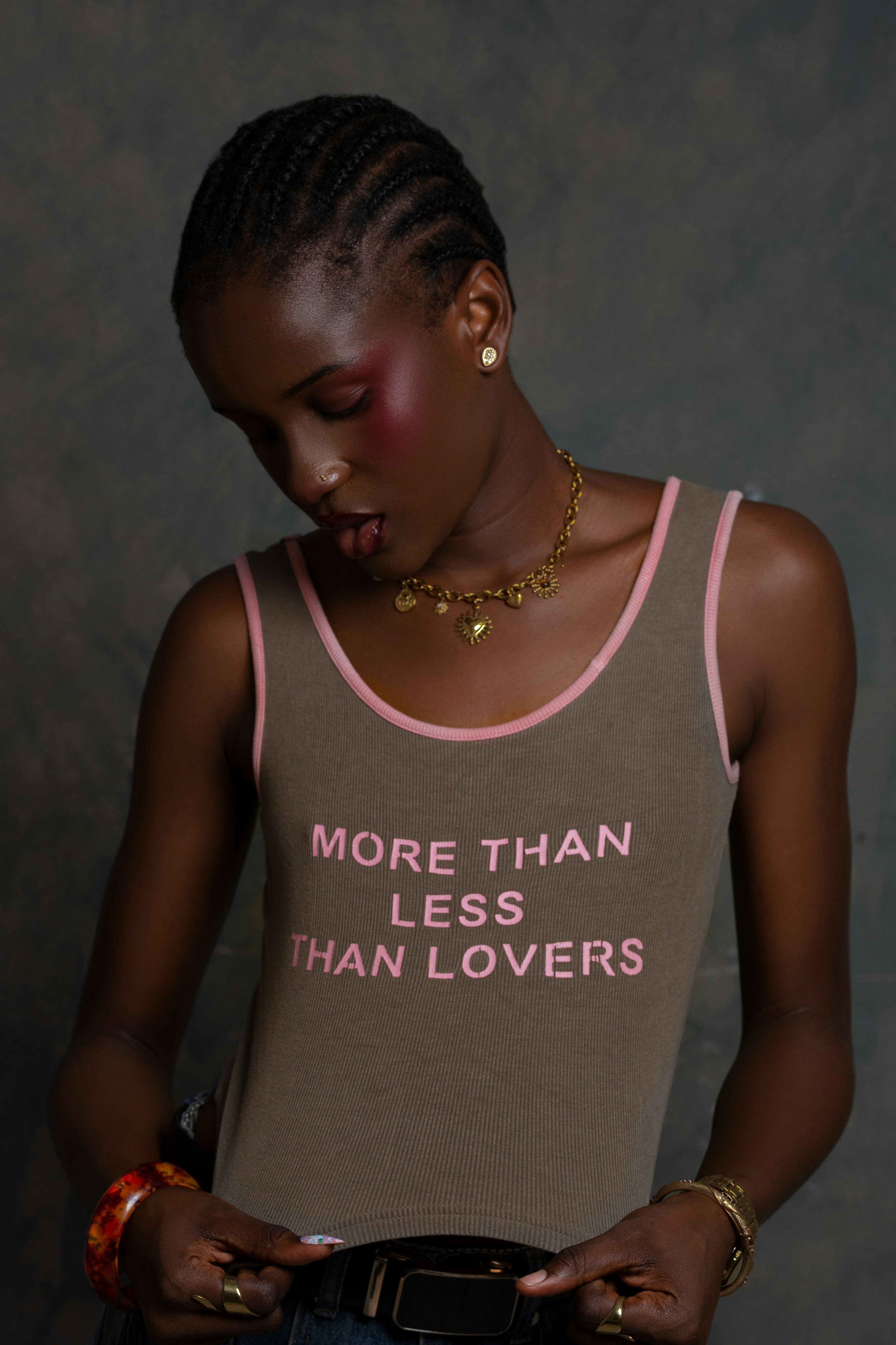 A person wearing a brown tank top with pink text looking down