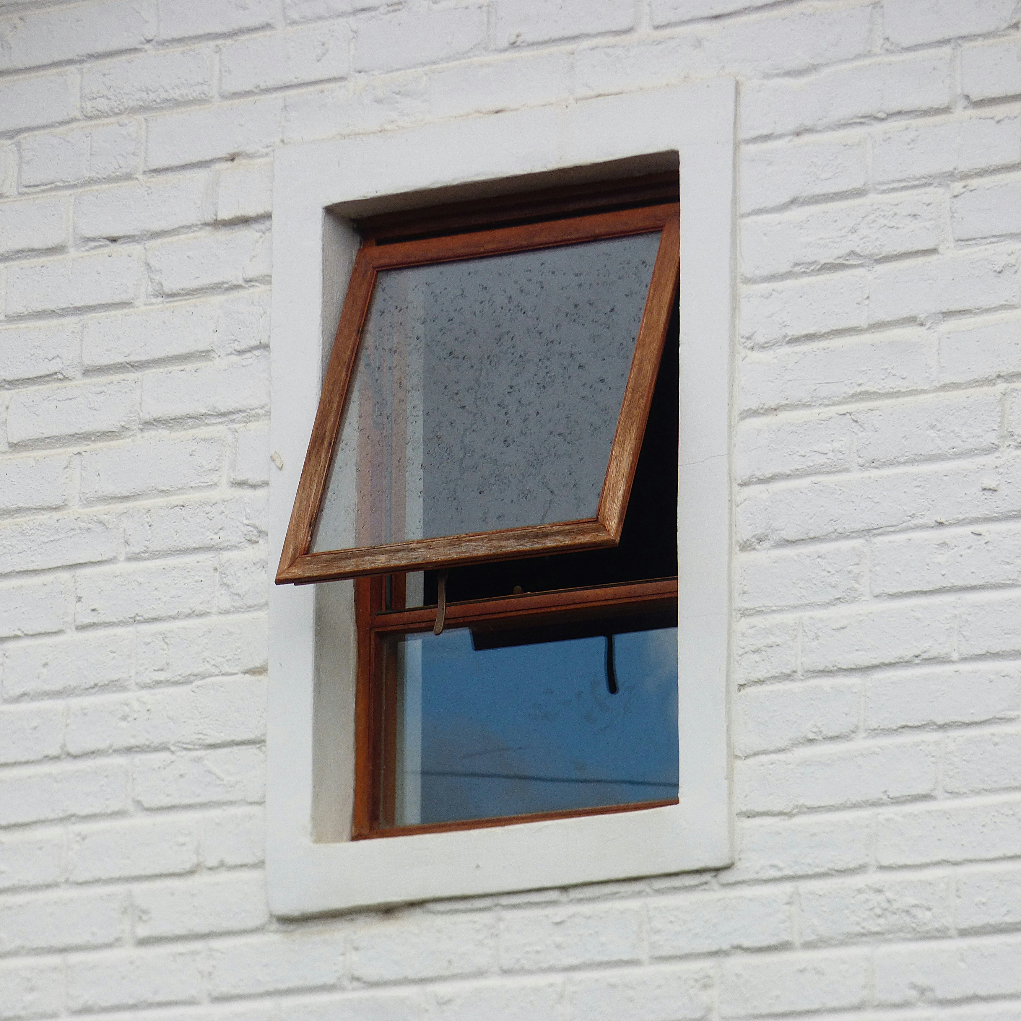 An open wooden window frame set into a white painted brick wall