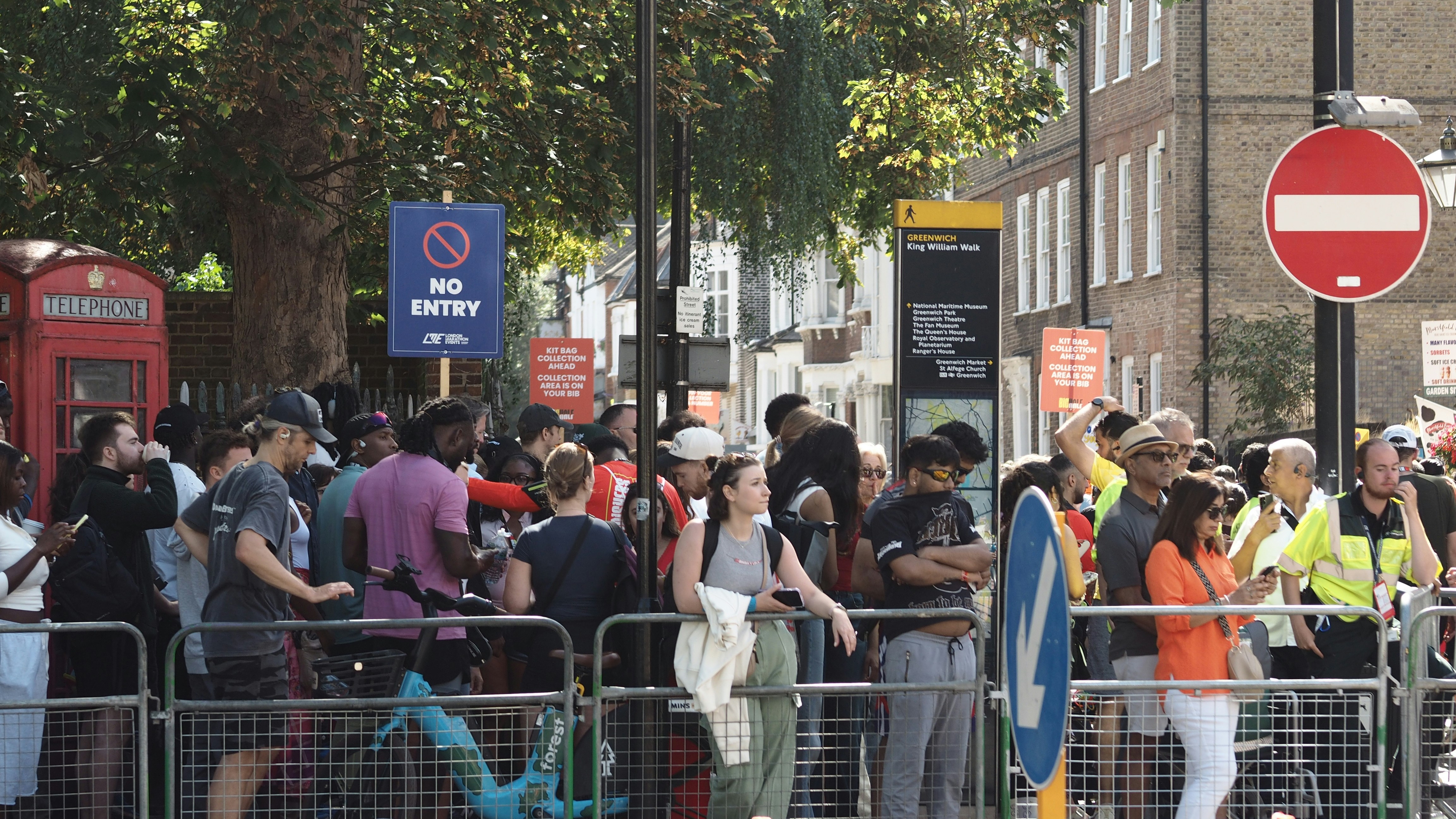 A crowd of people waiting behind metal barriers on King William Walk in London