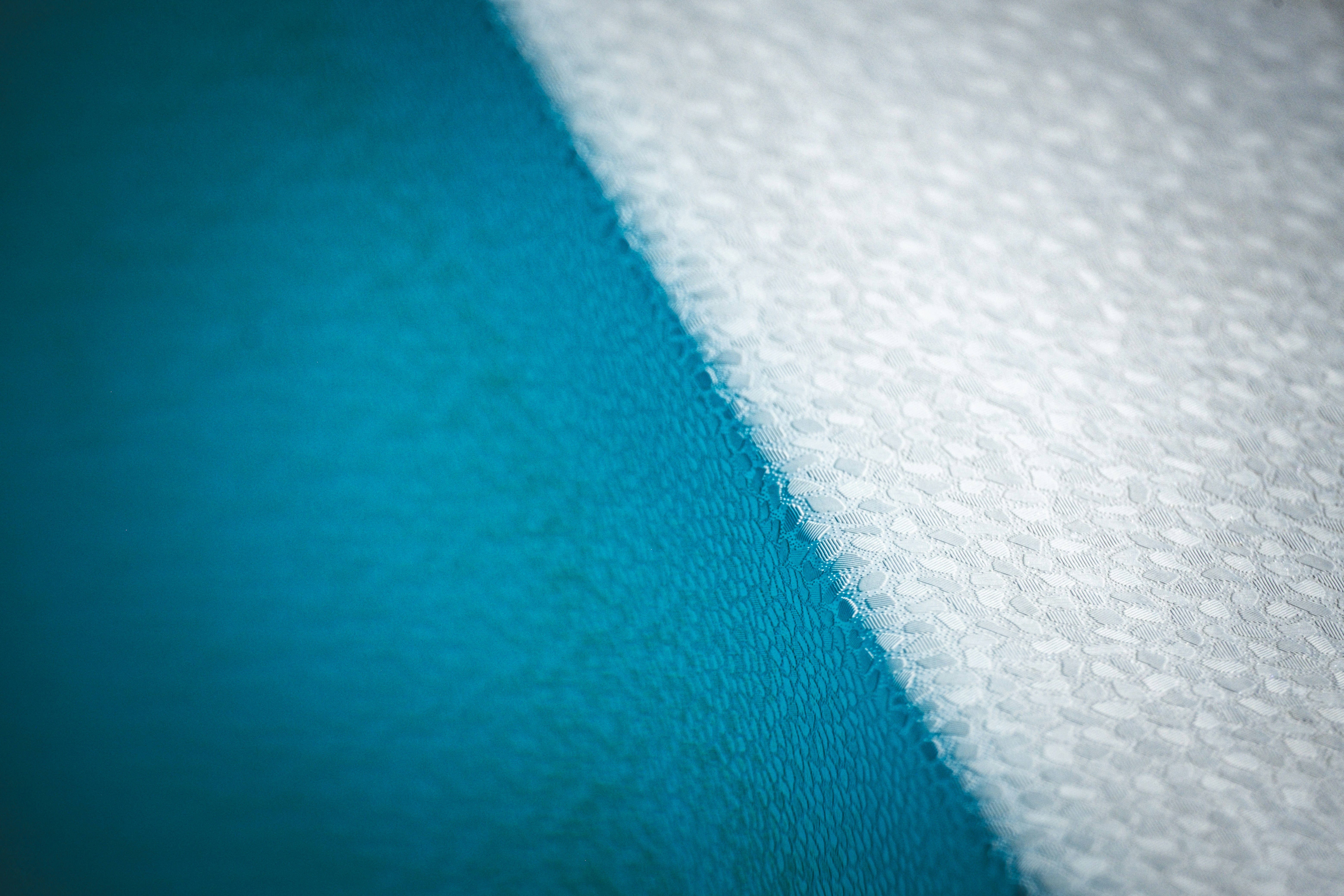 A diagonal division between a smooth teal surface and a textured white fabric