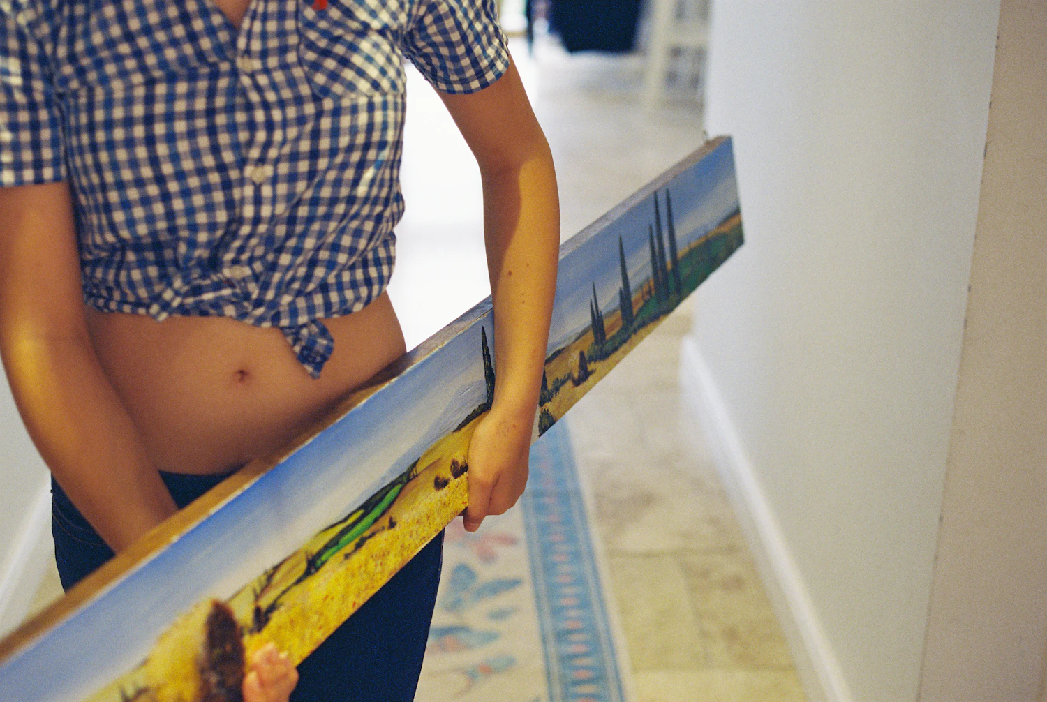A long painting carried down a corridor on its edge
