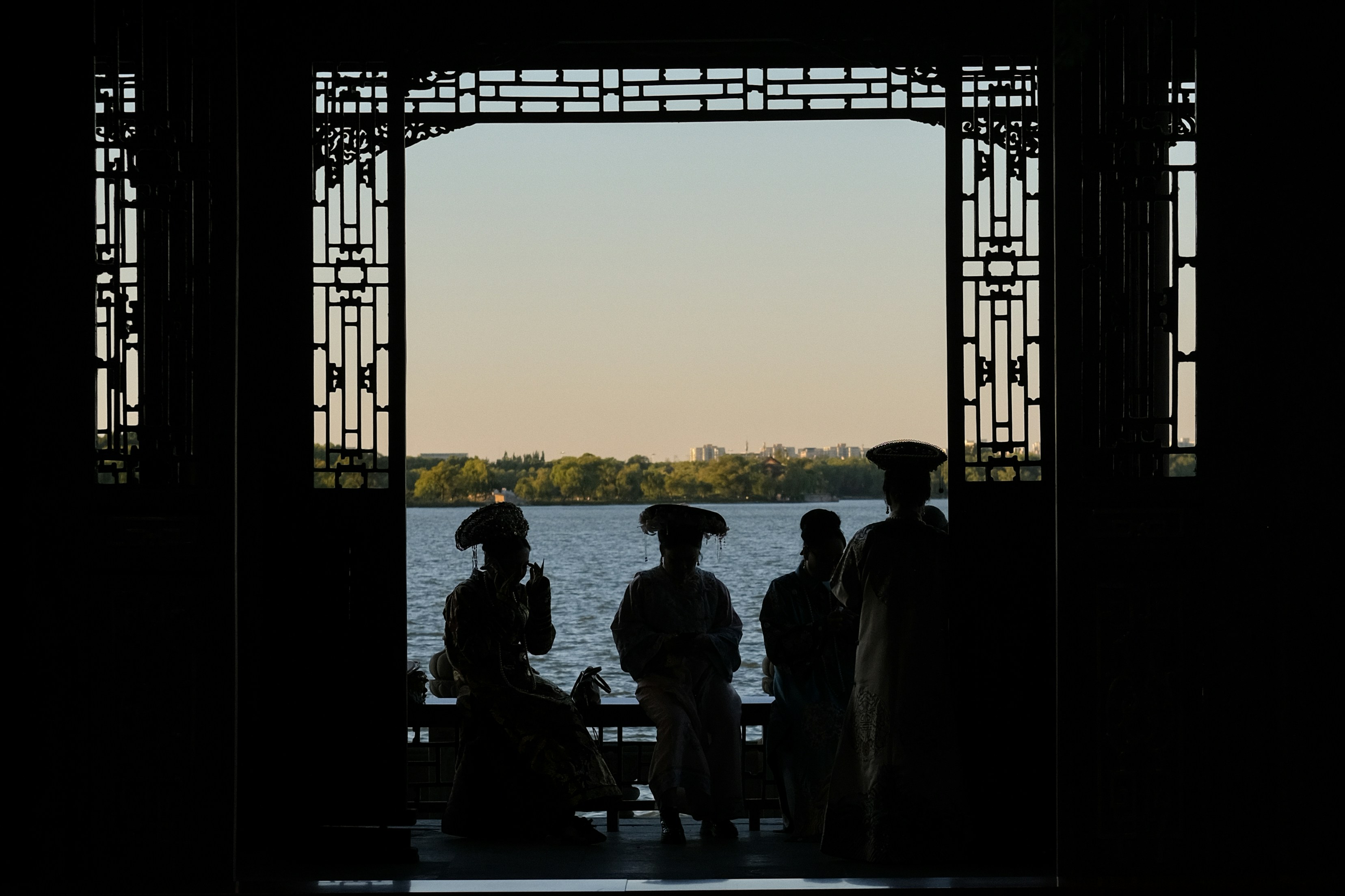 Quatre personnes en couvre-chef traditionnel silhouette contre un lac et des arbres lointains
