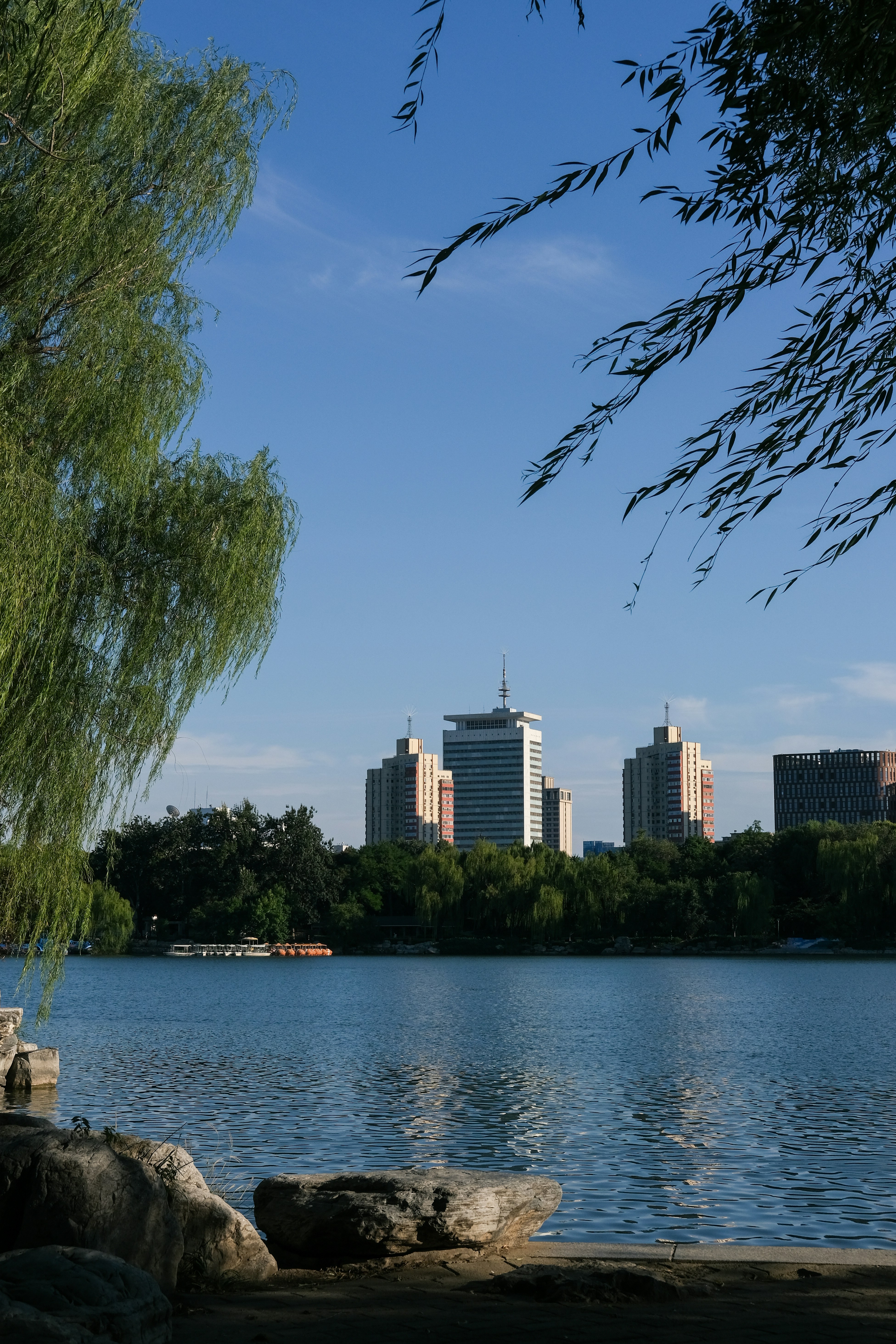 Un lac calme reflétant un ciel bleu clair avec des bâtiments de la ville au loin