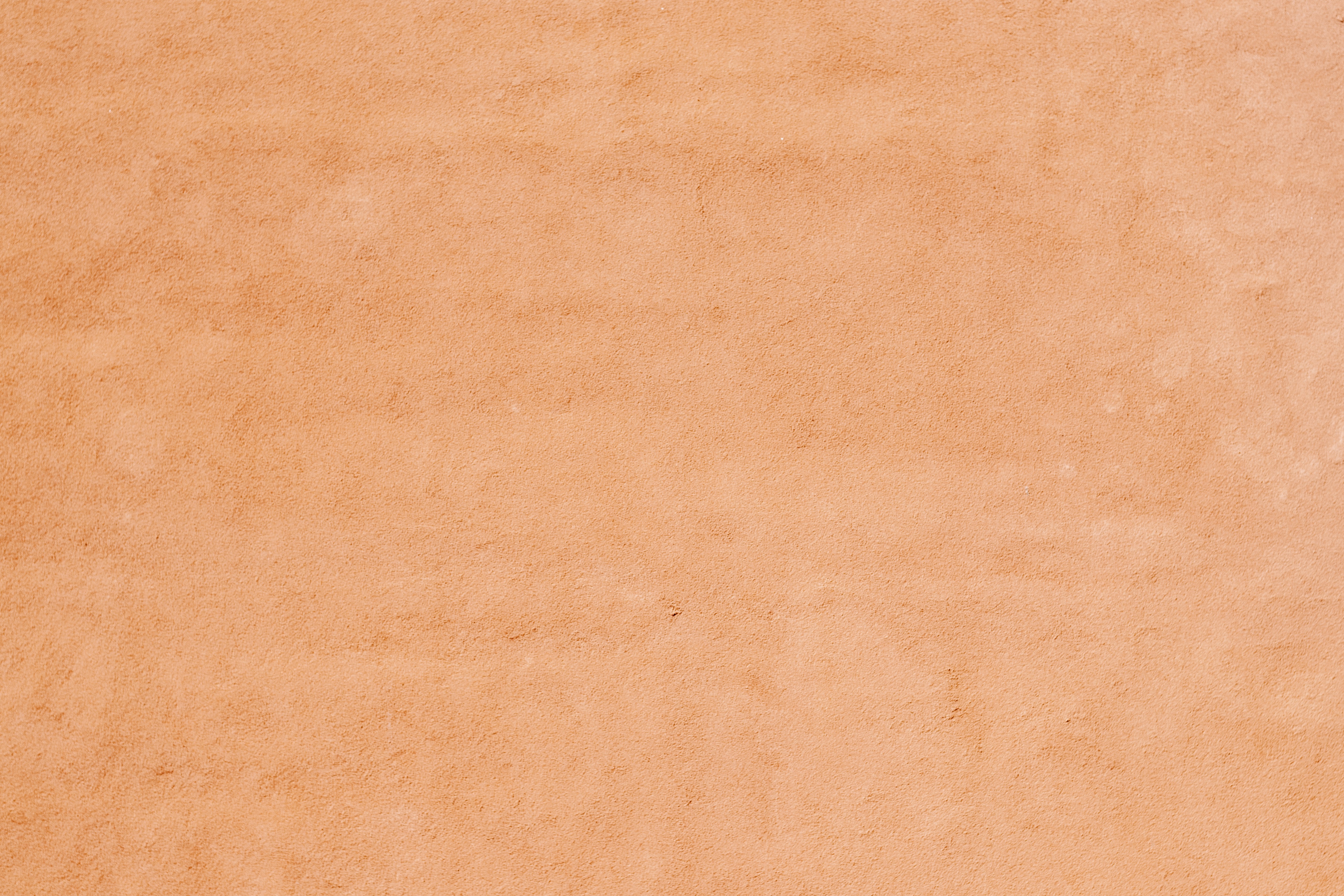 A textured peach colored plaster wall with a matte finish