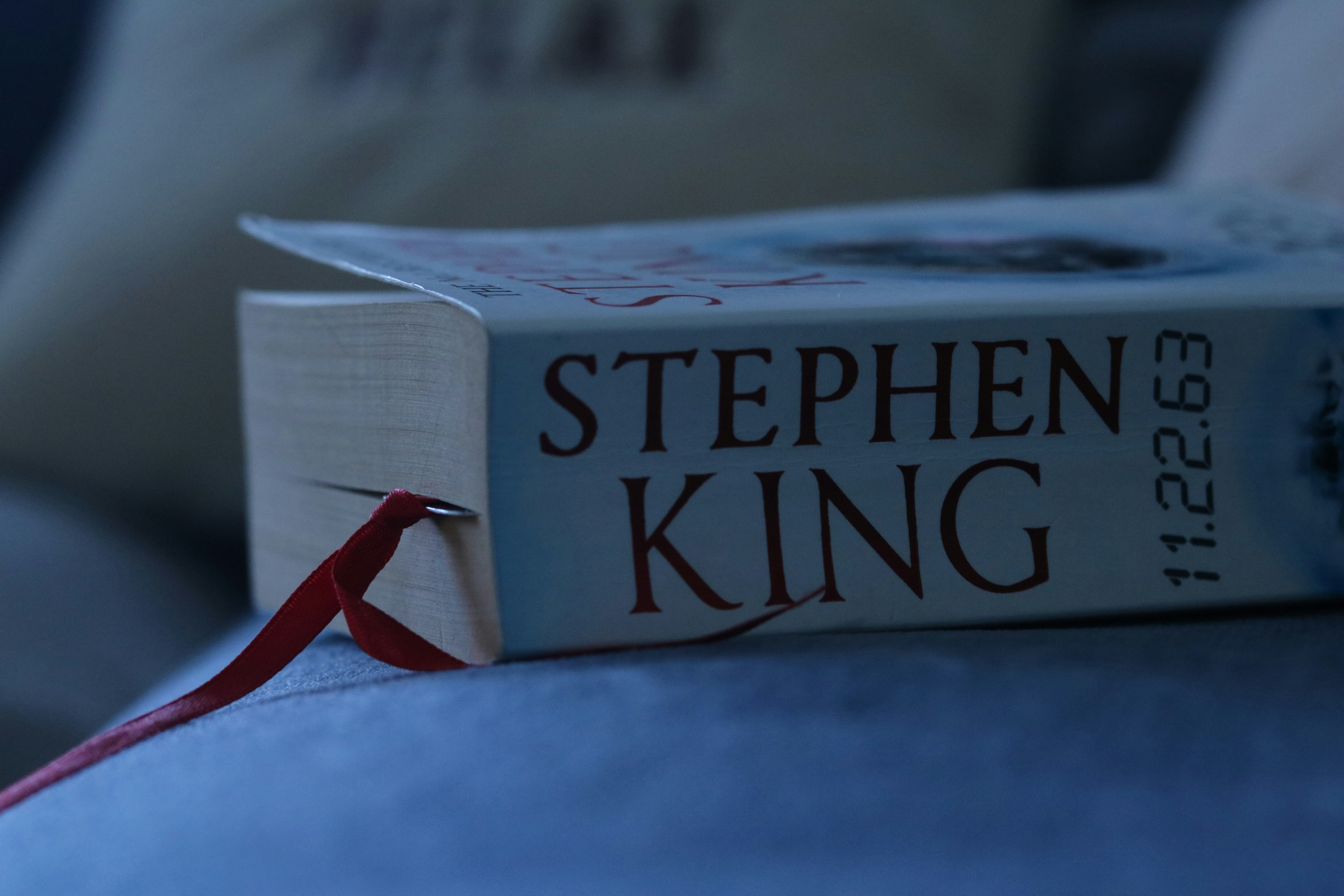 A book with a red ribbon bookmark resting on a soft blue surface