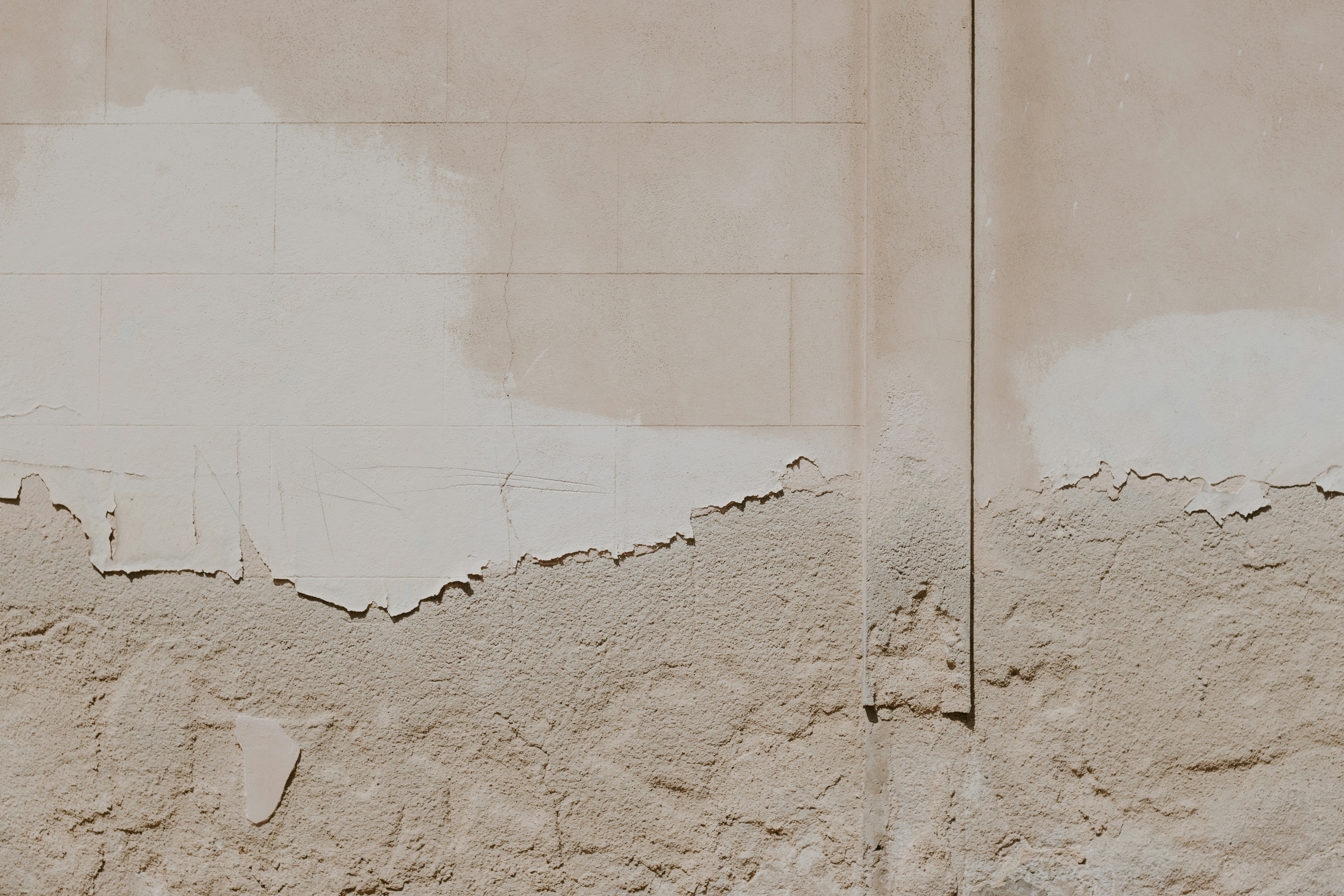 Weathered beige wall with peeling plaster