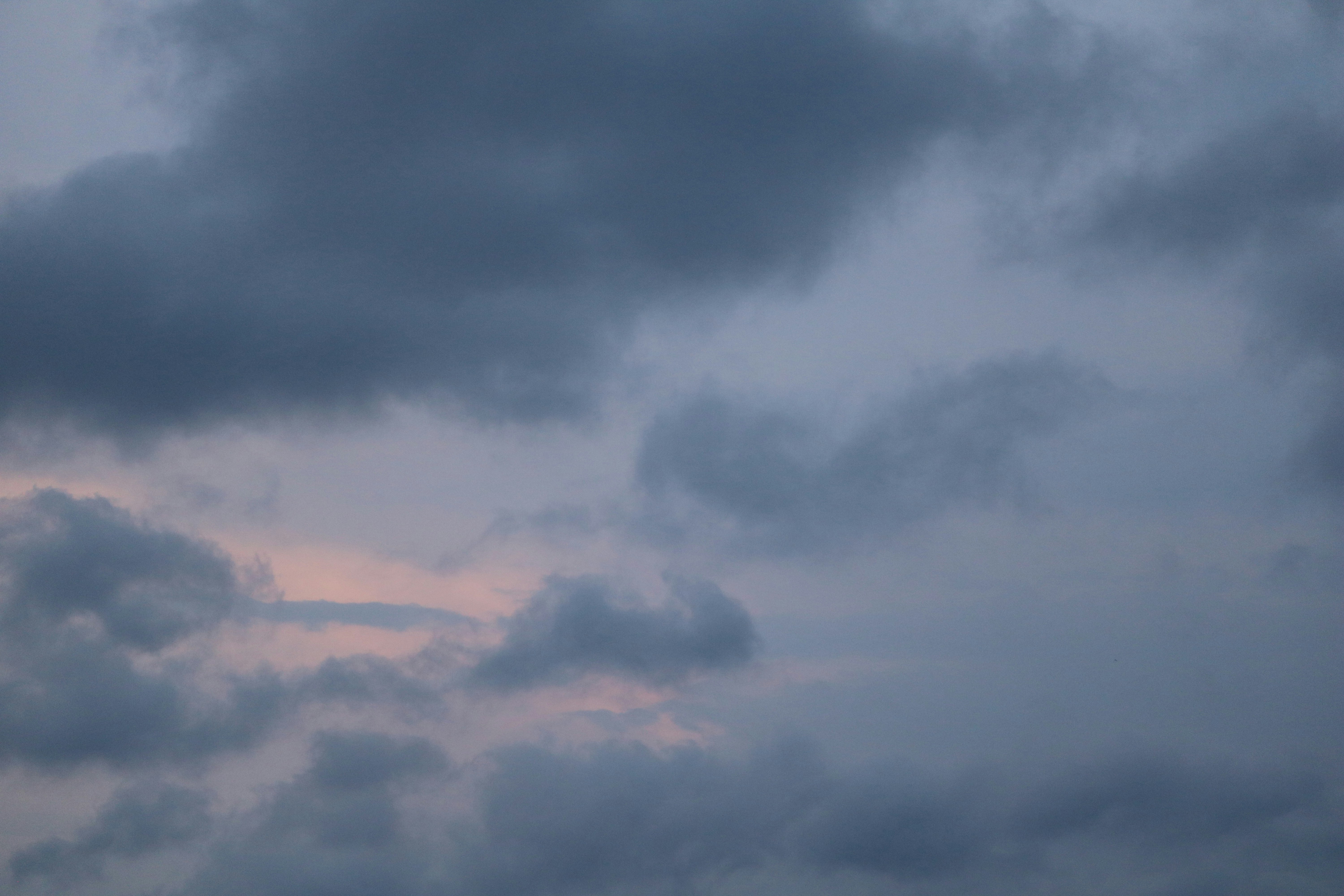 Dark grey clouds with a hint of soft pink light in the sky