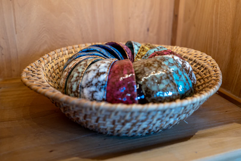 Colourful glazed ceramic bowls nested in a woven wicker basket