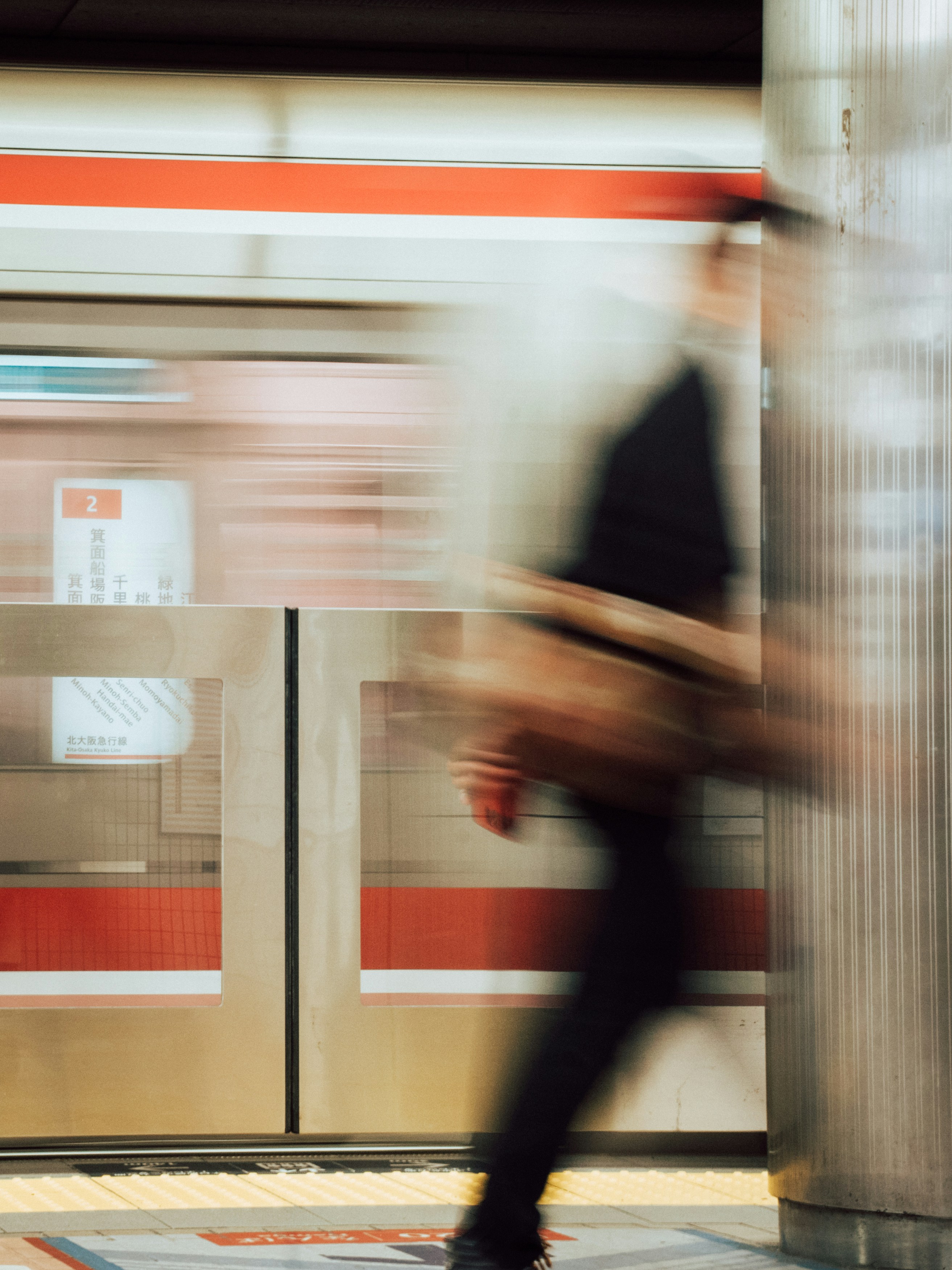 A blurred person walking past a train platform with red and white markings - 相关推荐