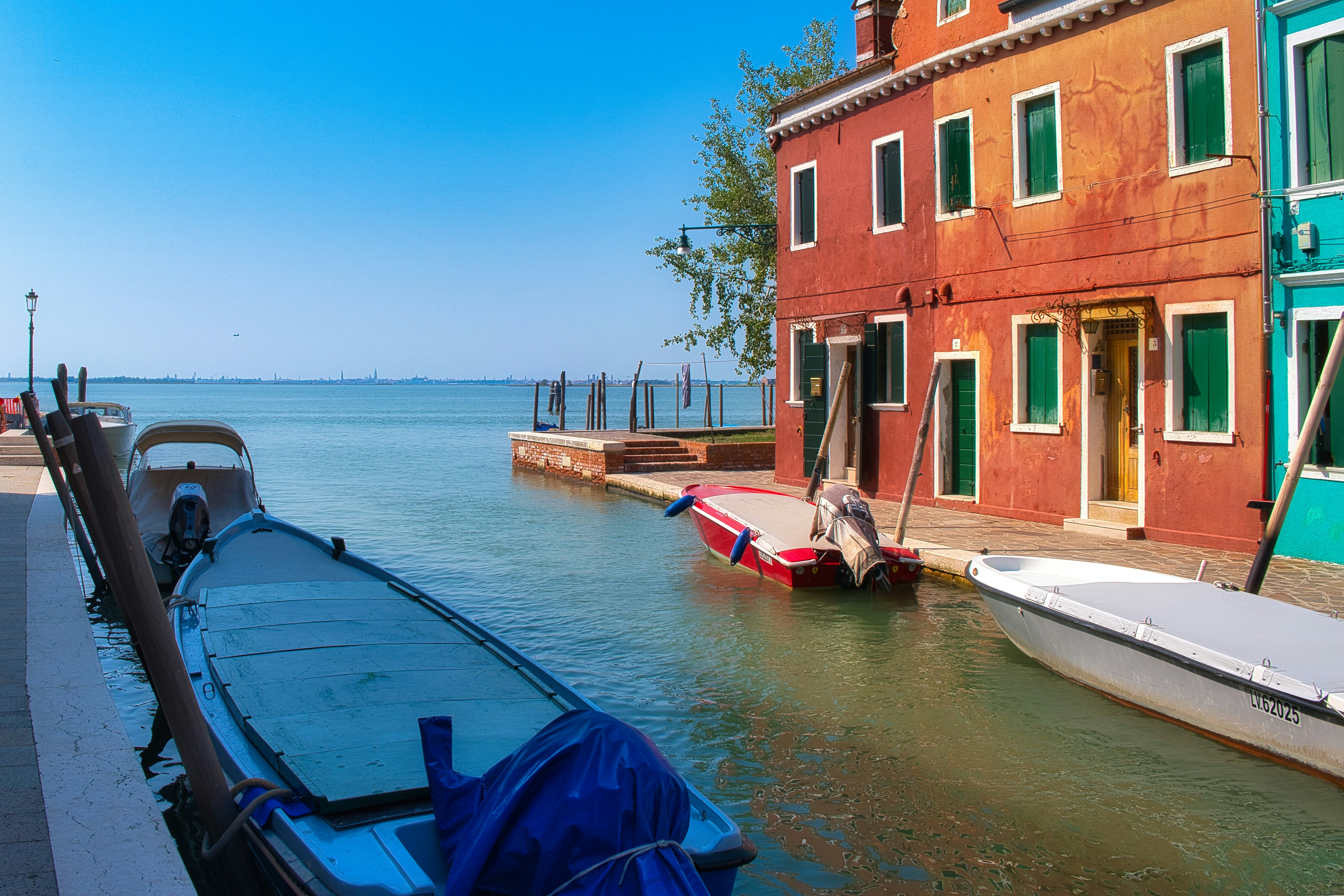 Boats moored in a canal beside colorful buildings on Burano island in Venice