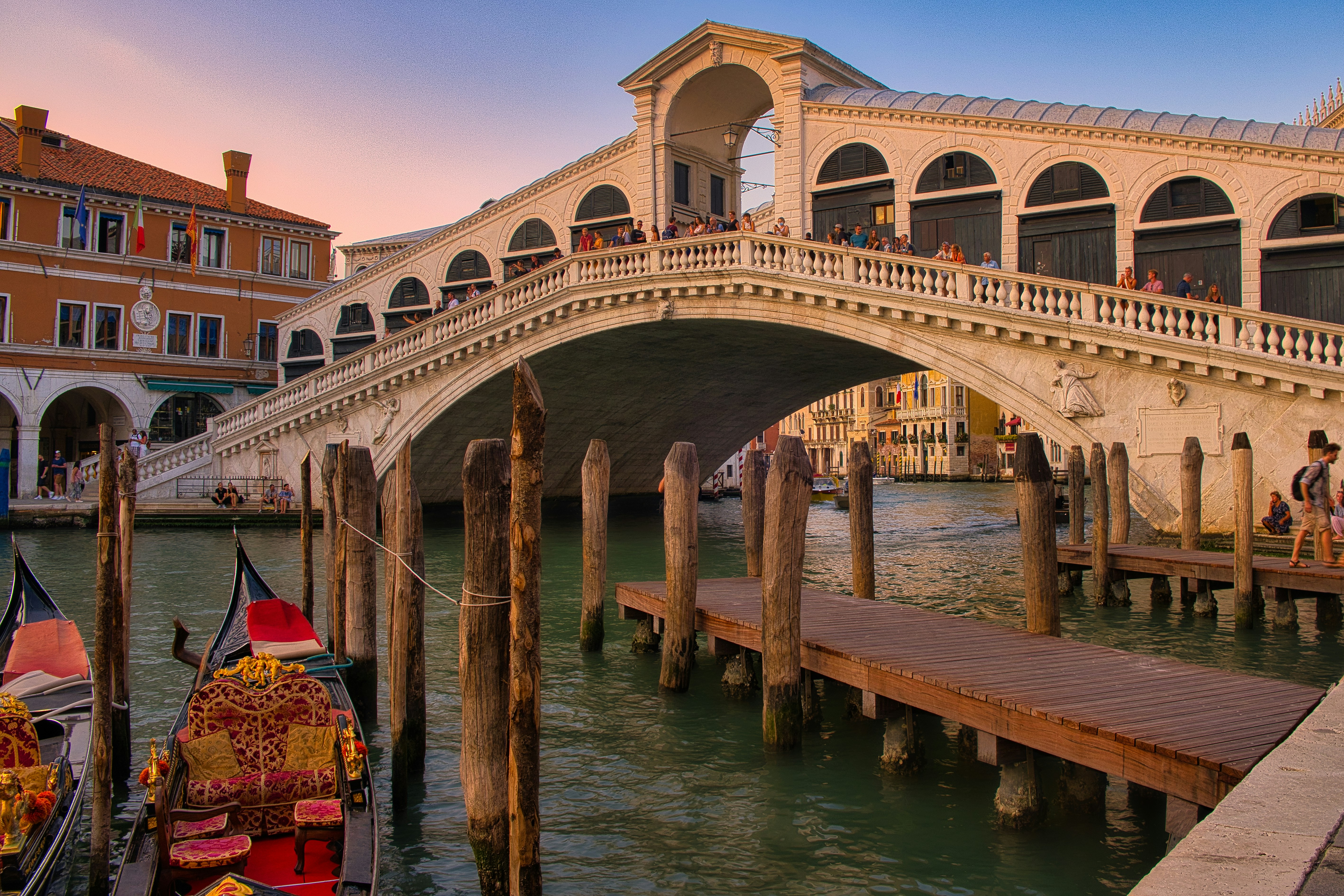 The Rialto Bridge over the Grand Canal in Venice with gondolas at wooden moorings