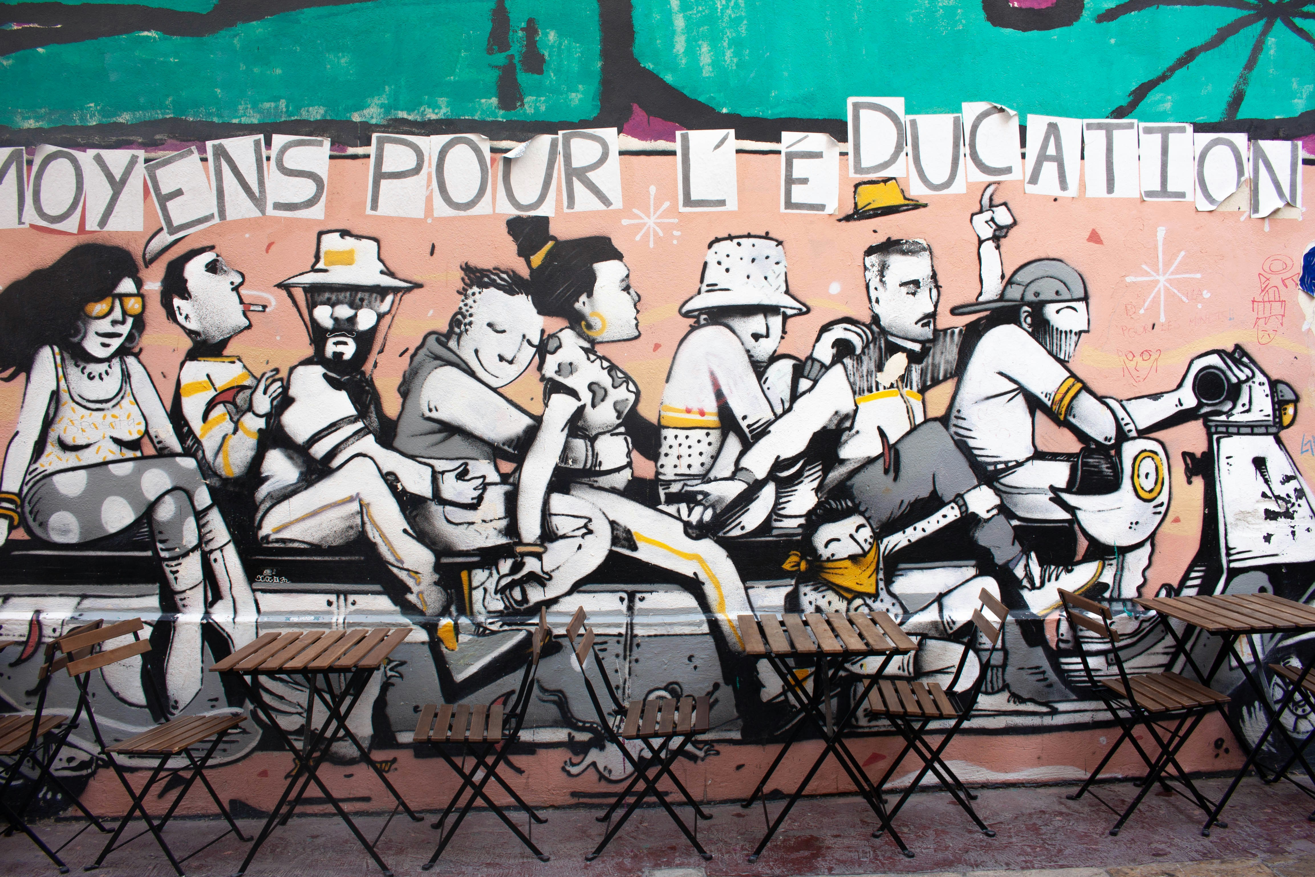 A mural of people riding a scooter with text reading MOYENS POUR L'EDUCATION