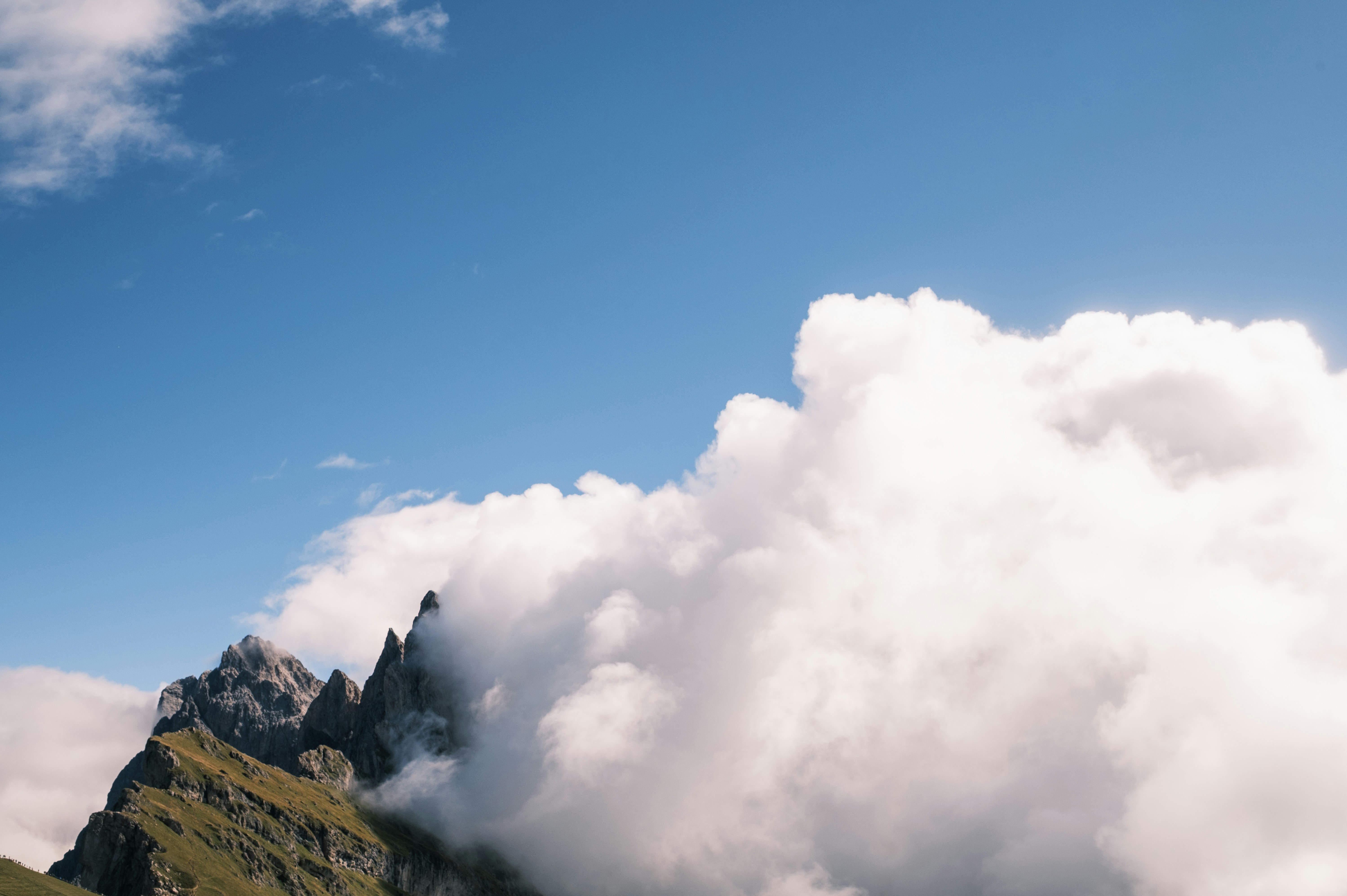 Rocky mountain peaks partially obscured by thick white clouds against a blue sky