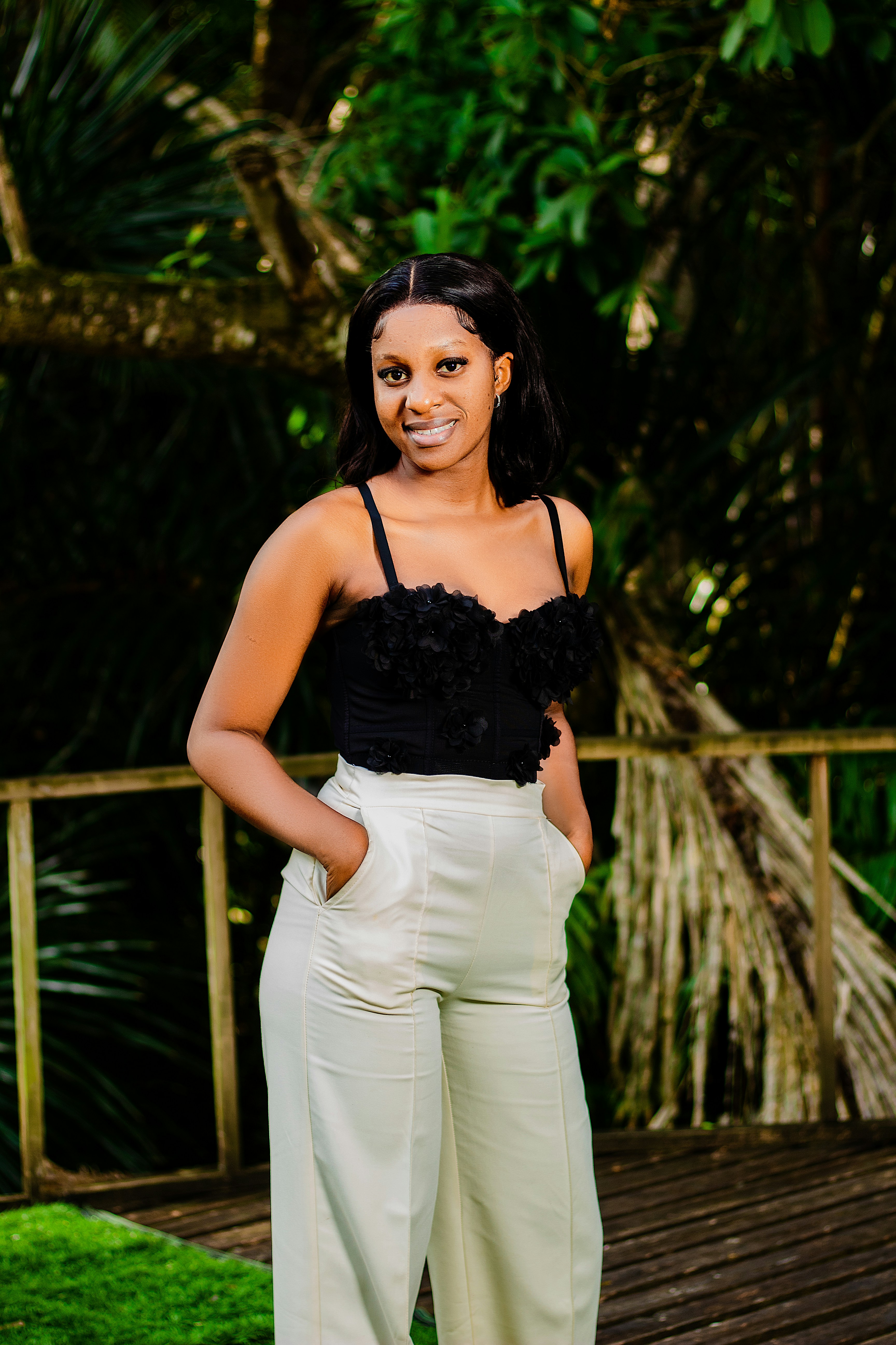 A woman in a black floral corset and cream trousers on a wooden deck