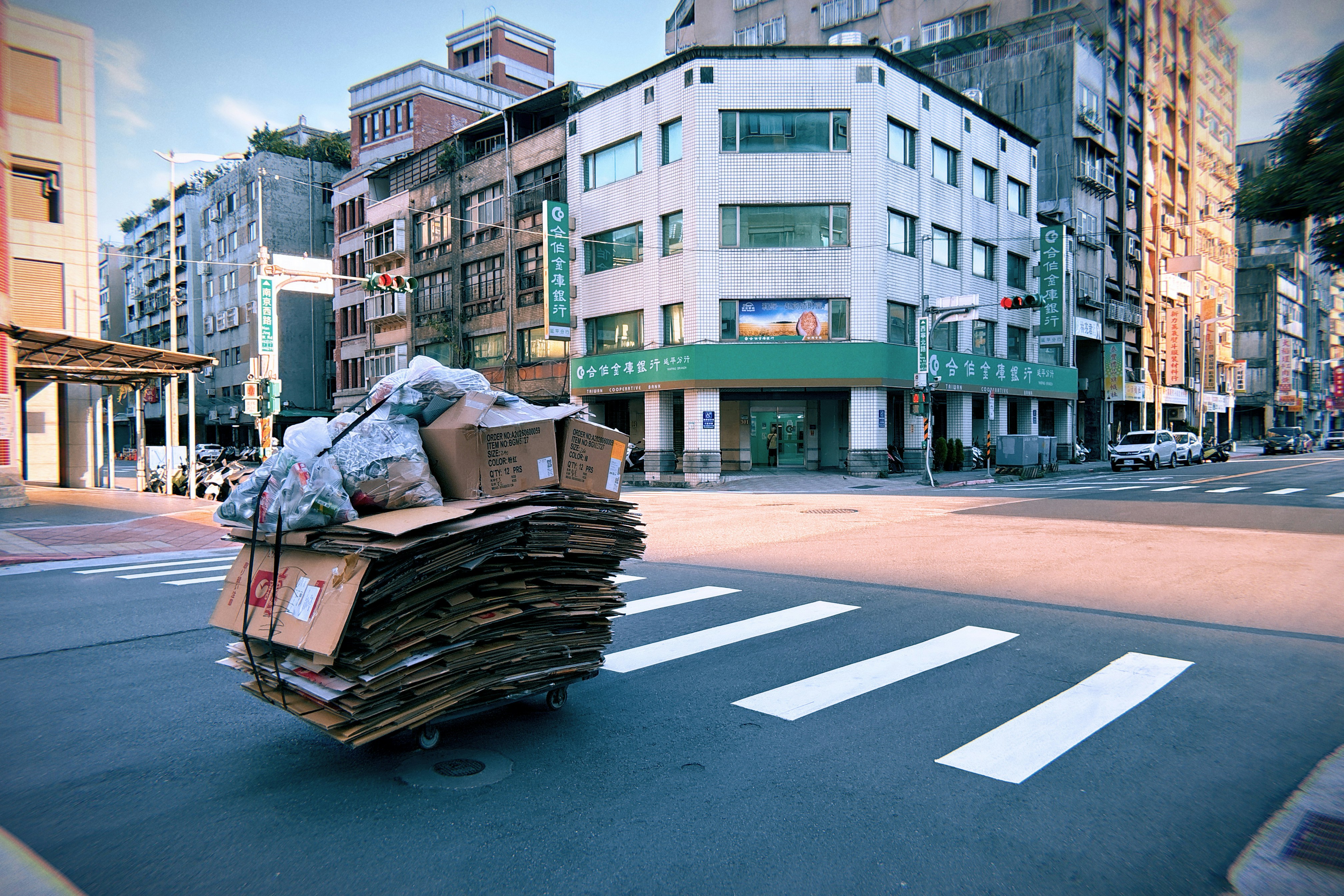 A cart piled high with cardboard boxes and plastic bags on a city crosswalk