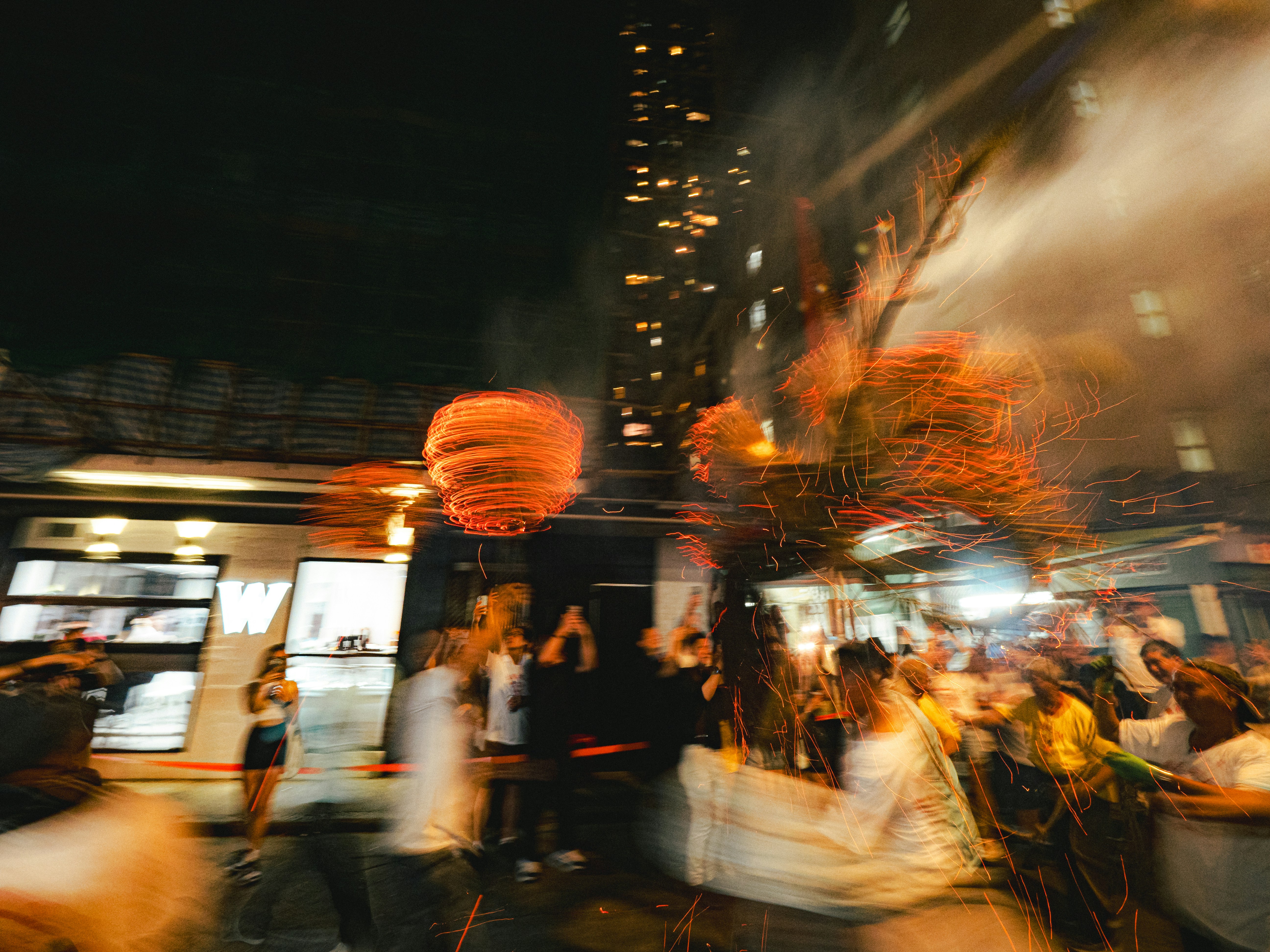 Long exposure of a spinning fire lantern and sparks at a night festival