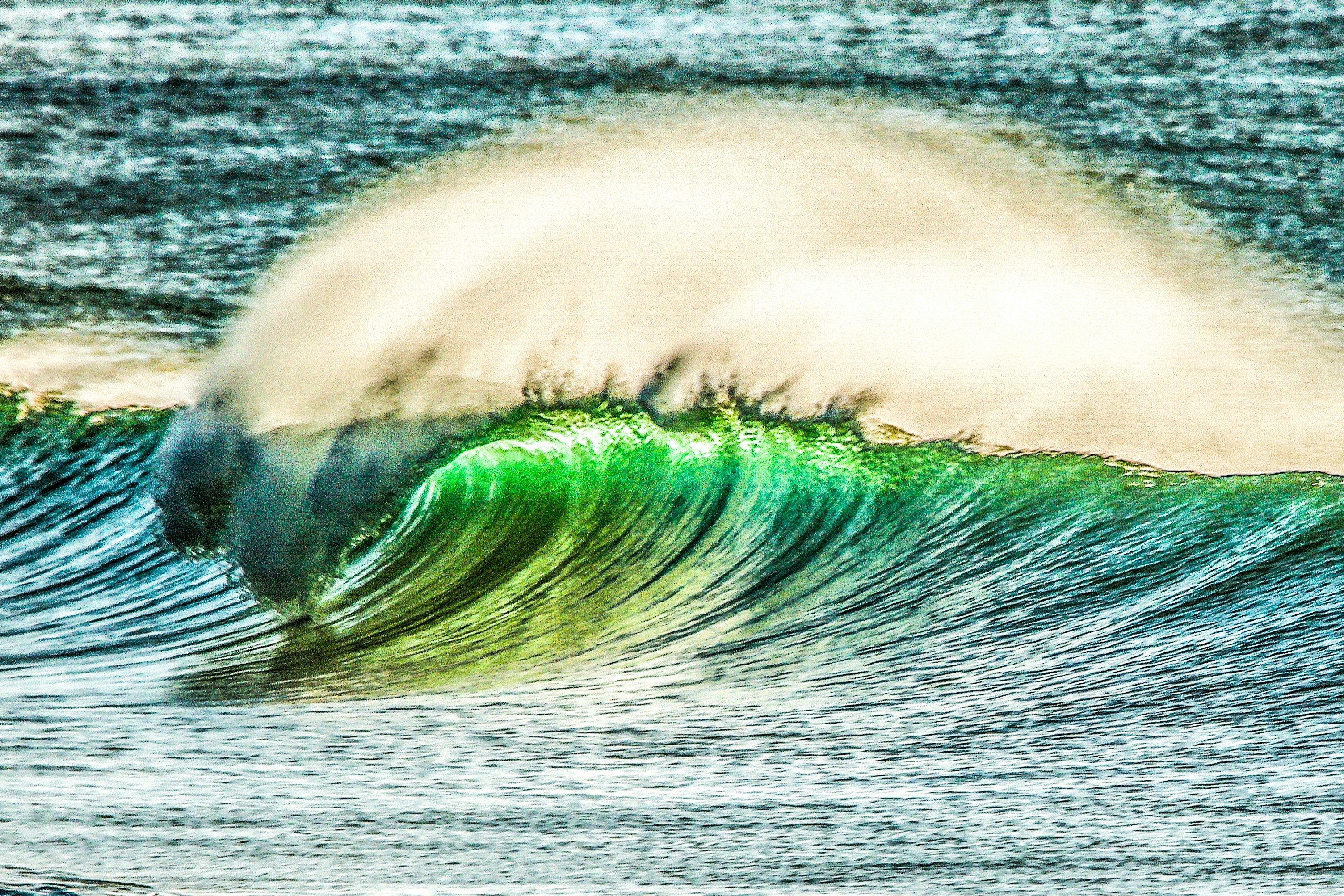 A bright green ocean wave curling and breaking with white sea spray
