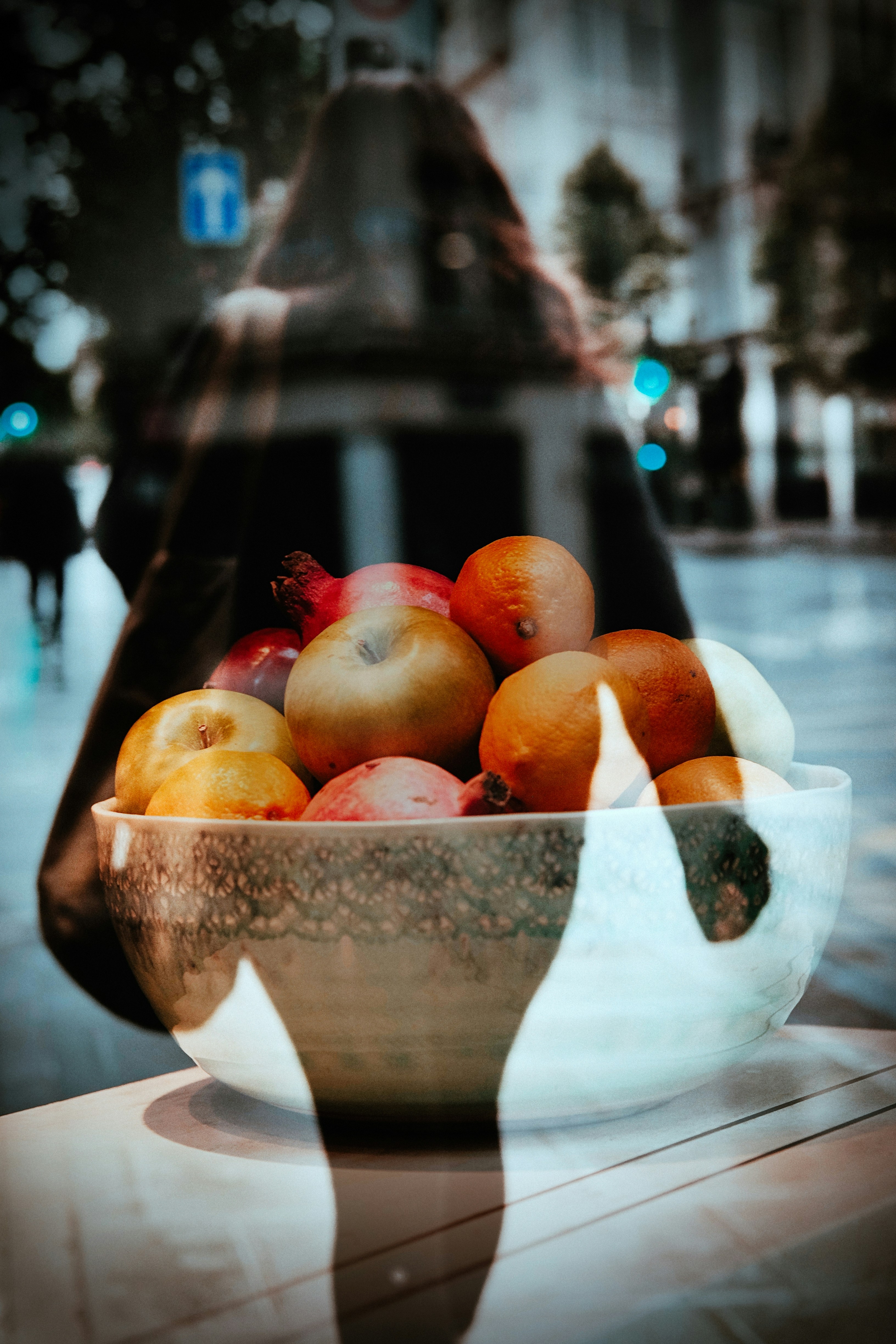 A bowl of mixed fruit including apples and oranges on a table
