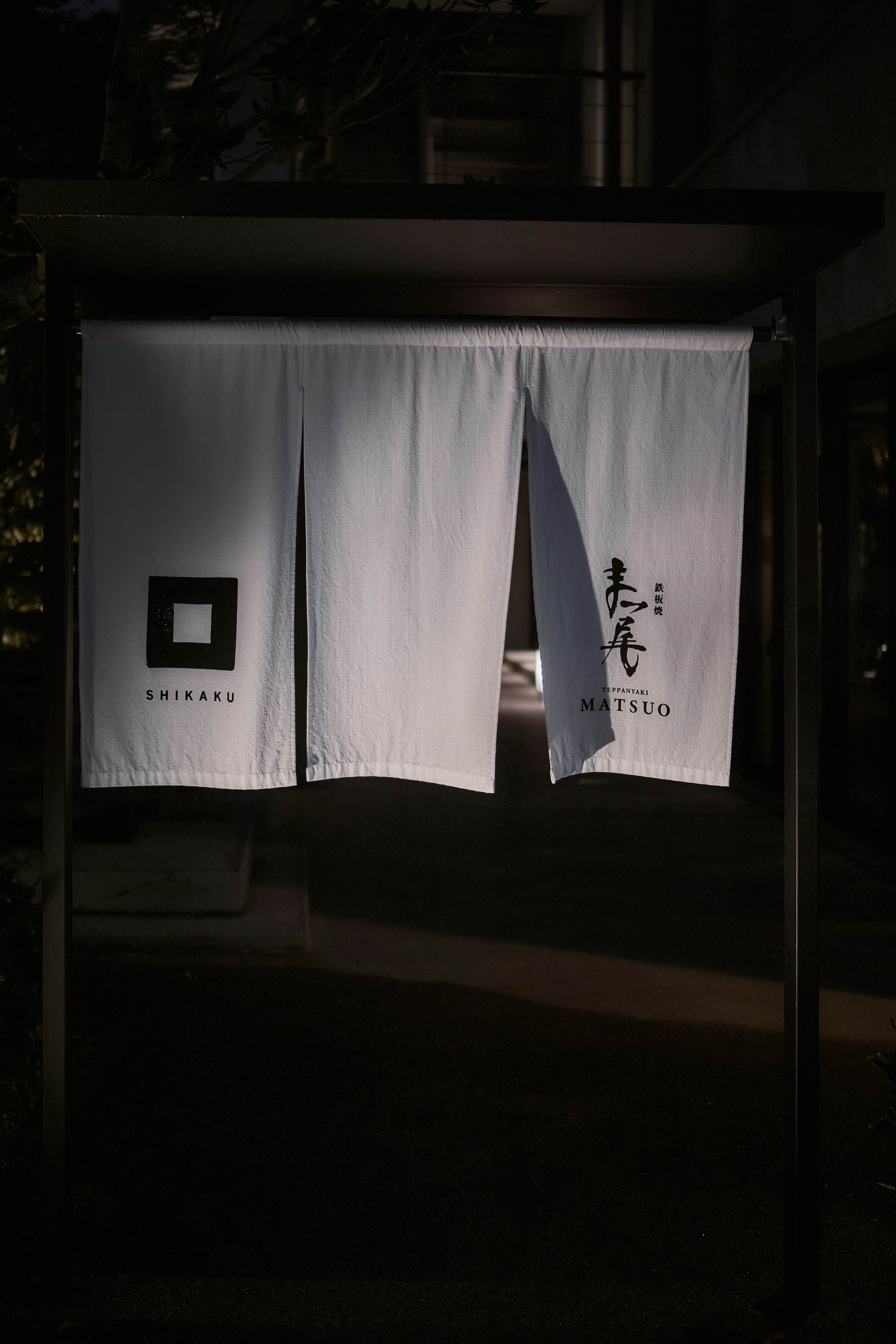 White noren curtains with black logos hanging in a doorway in Naha, Okinawa