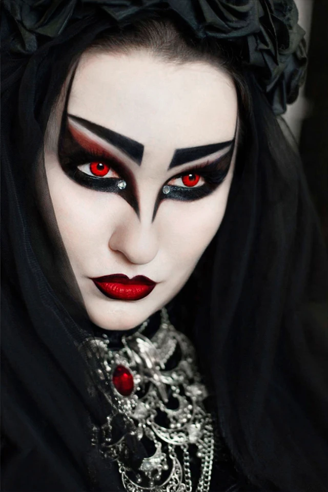 A person with red eyes, dark gothic make-up and a black veil