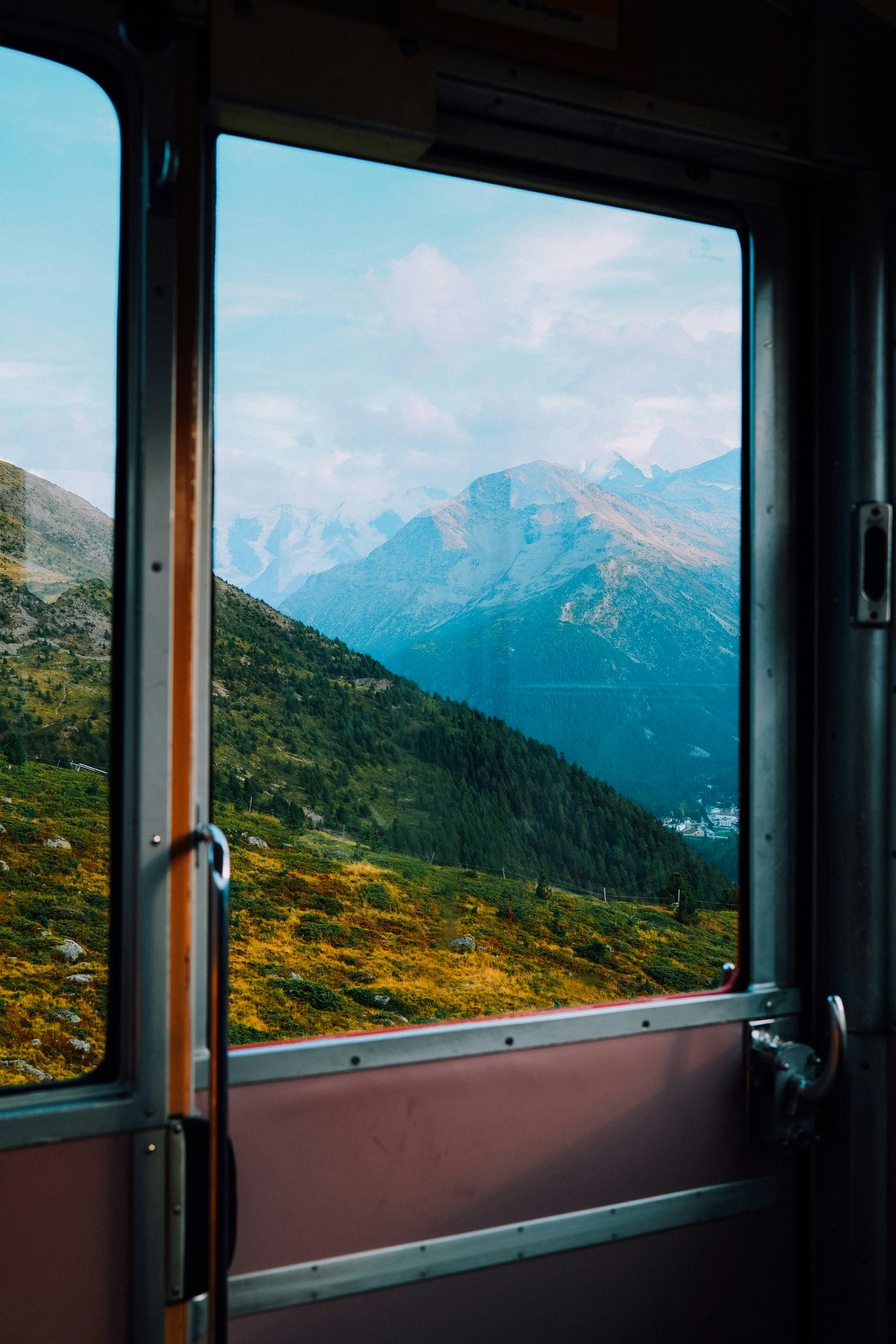 A view of green mountain slopes through a train window