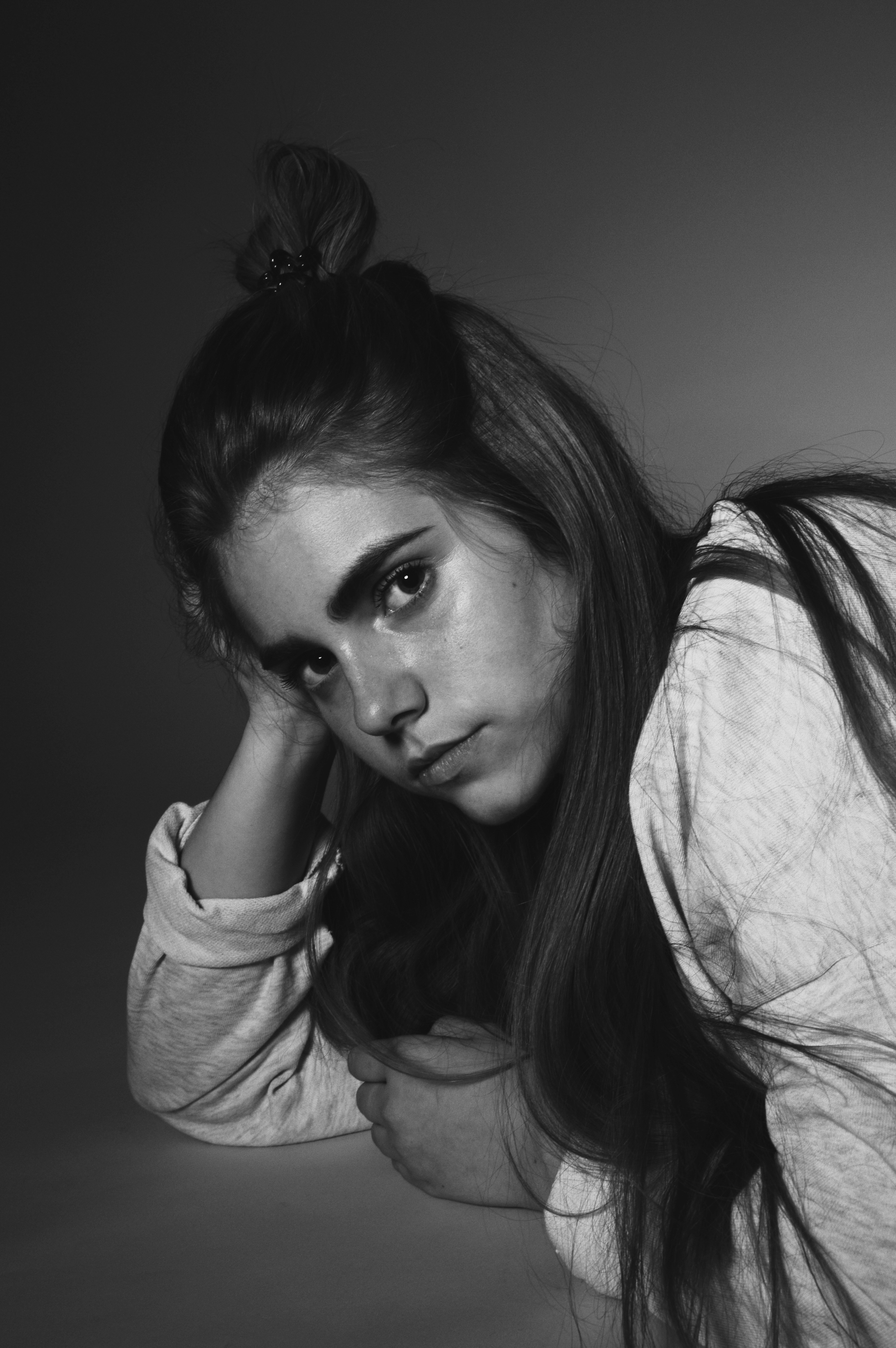 A woman with long hair in a top knot wearing a light sweatshirt