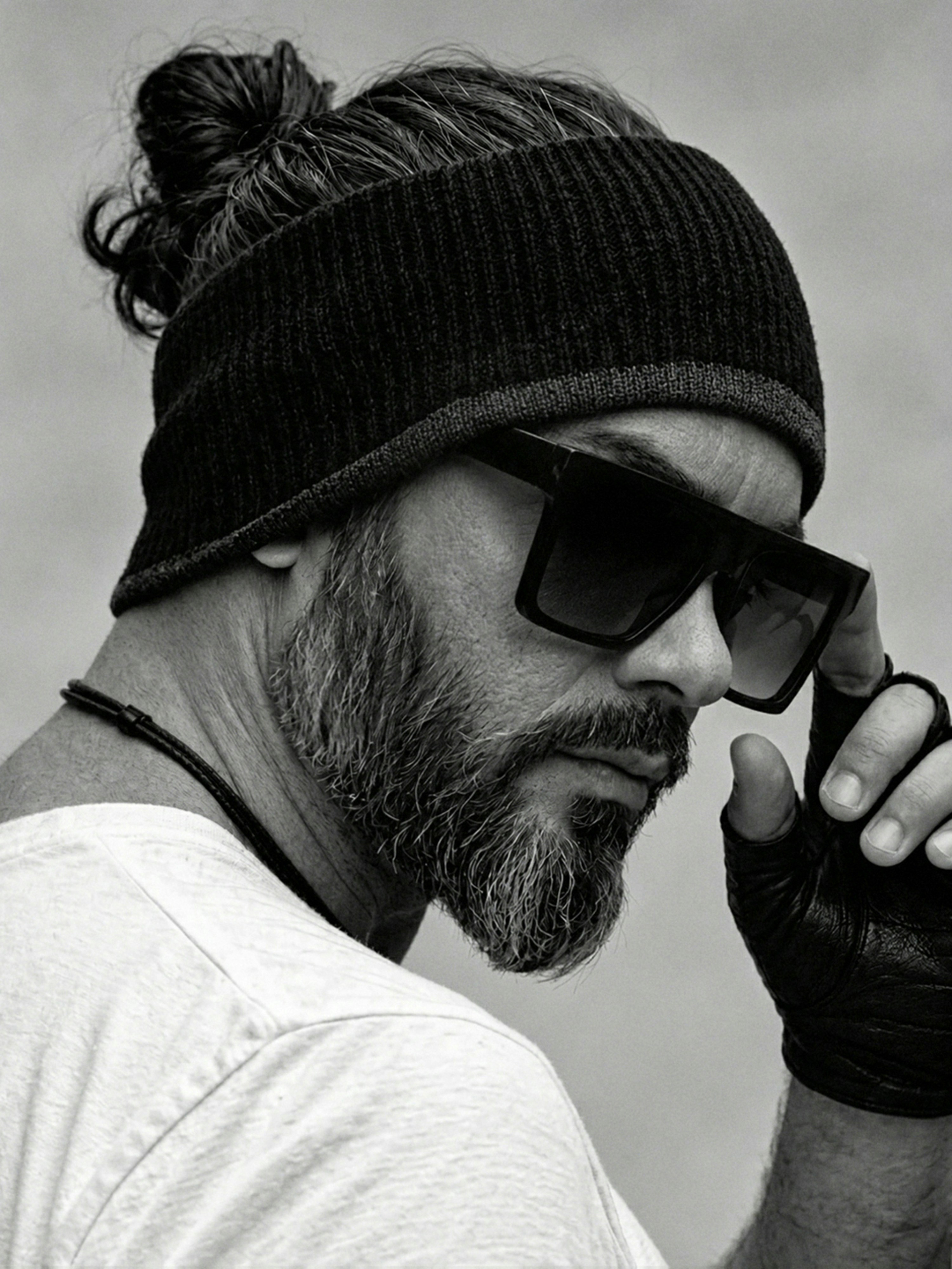 A man with a beard and hair in a bun wearing sunglasses and gloves