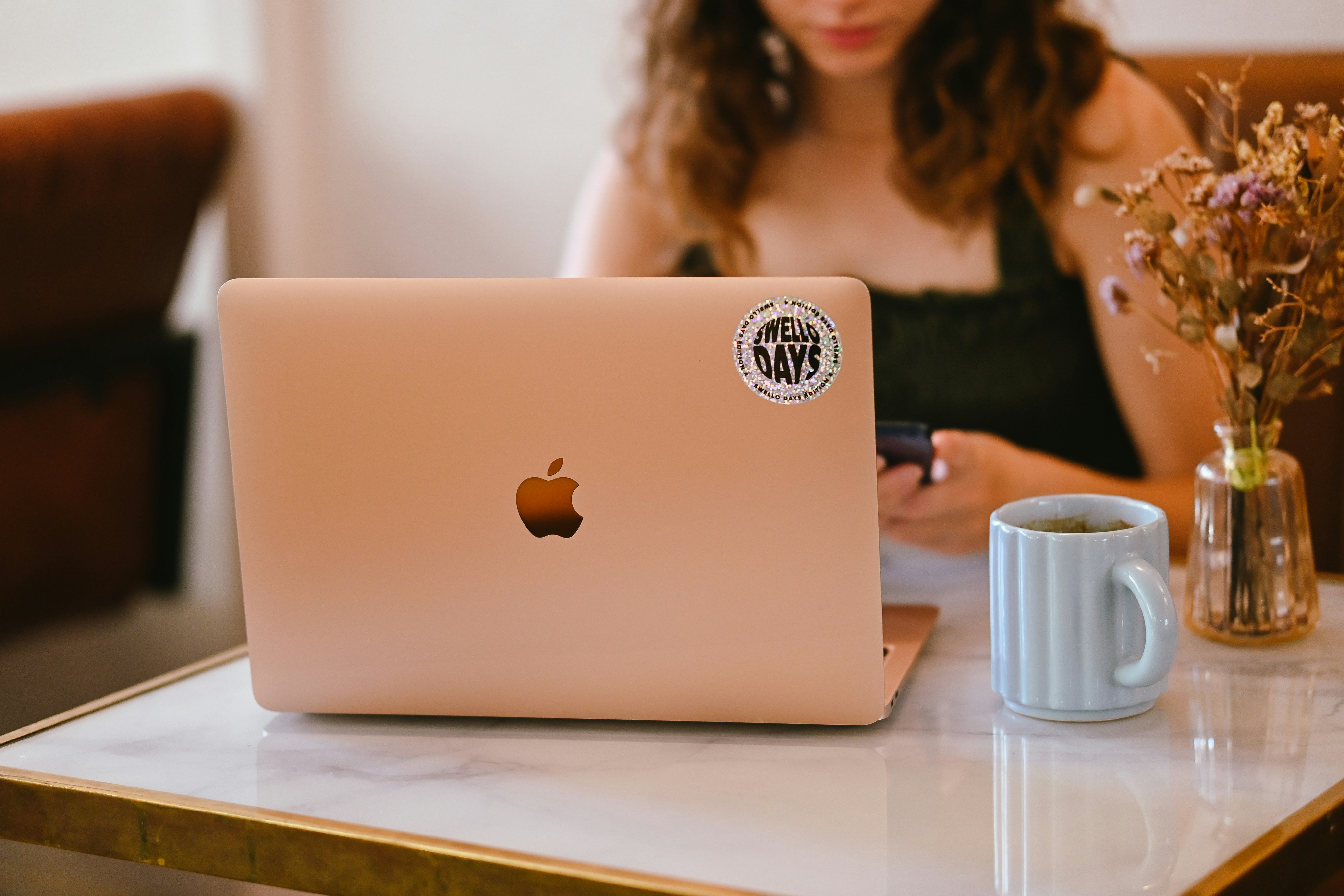 A person using a laptop with a sticker on a marble table