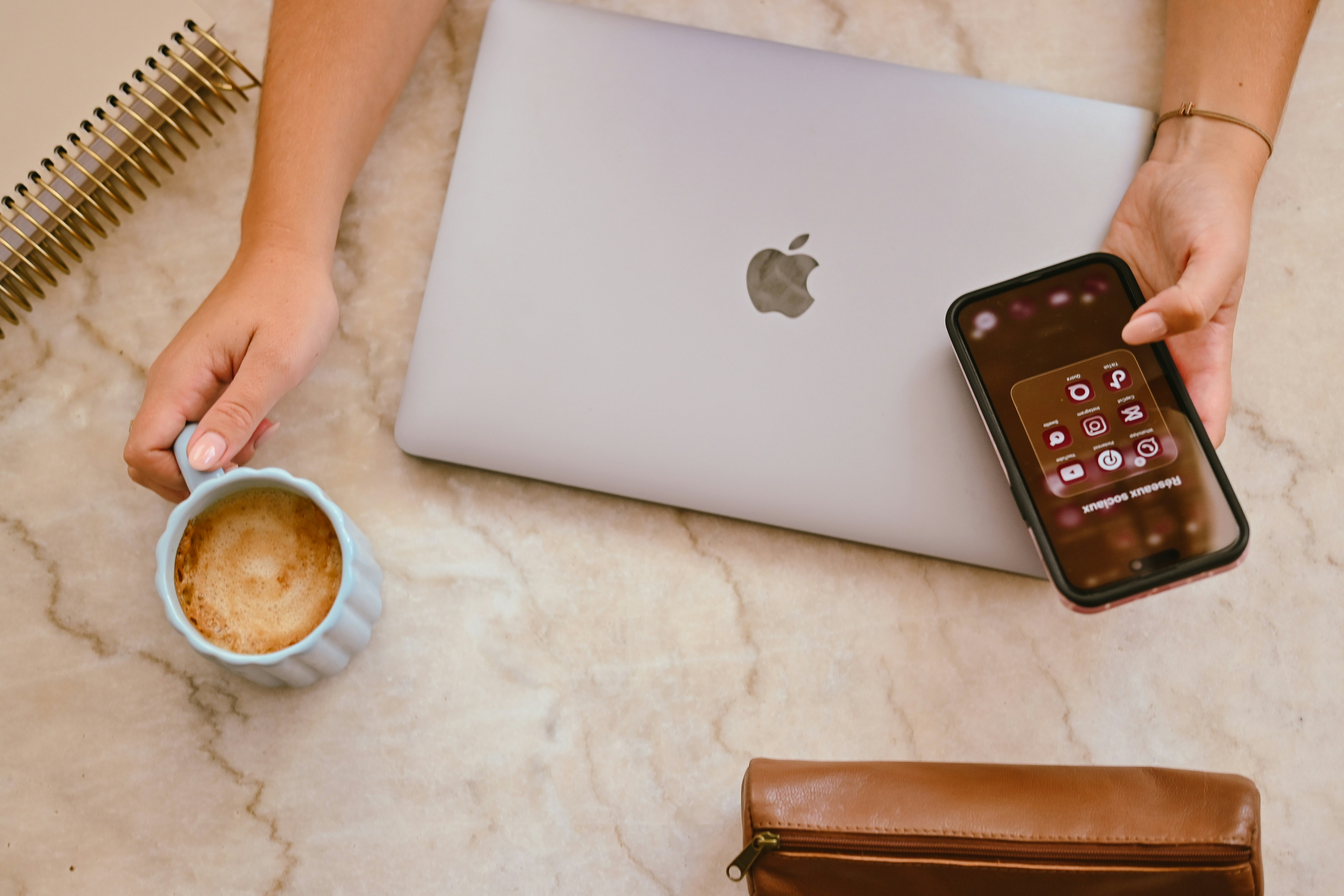 Hand holding a coffee and a smartphone showing social media apps