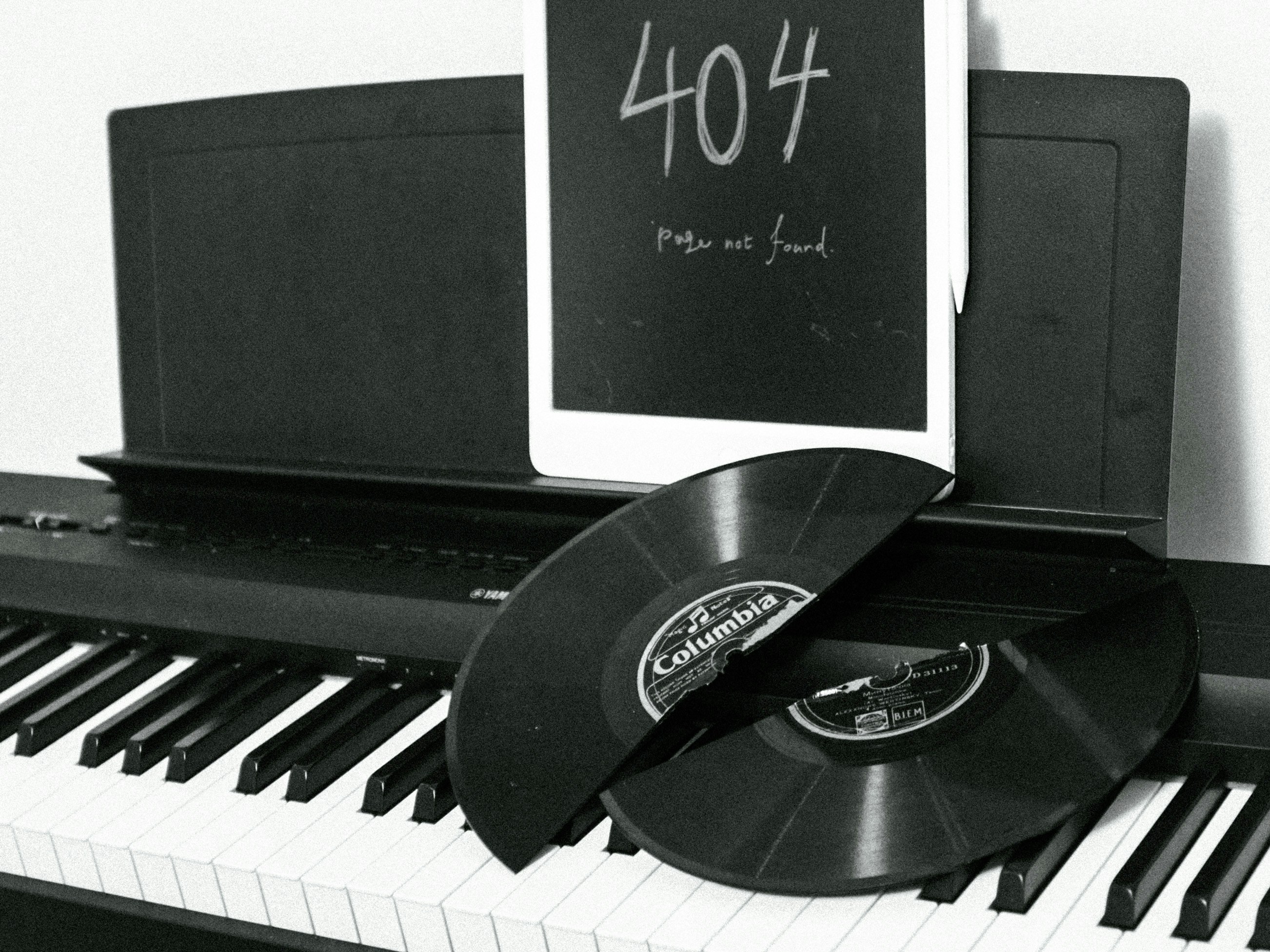Old records lie across piano keys while a chalk-drawn "404, Page not found" sits on the music stand.