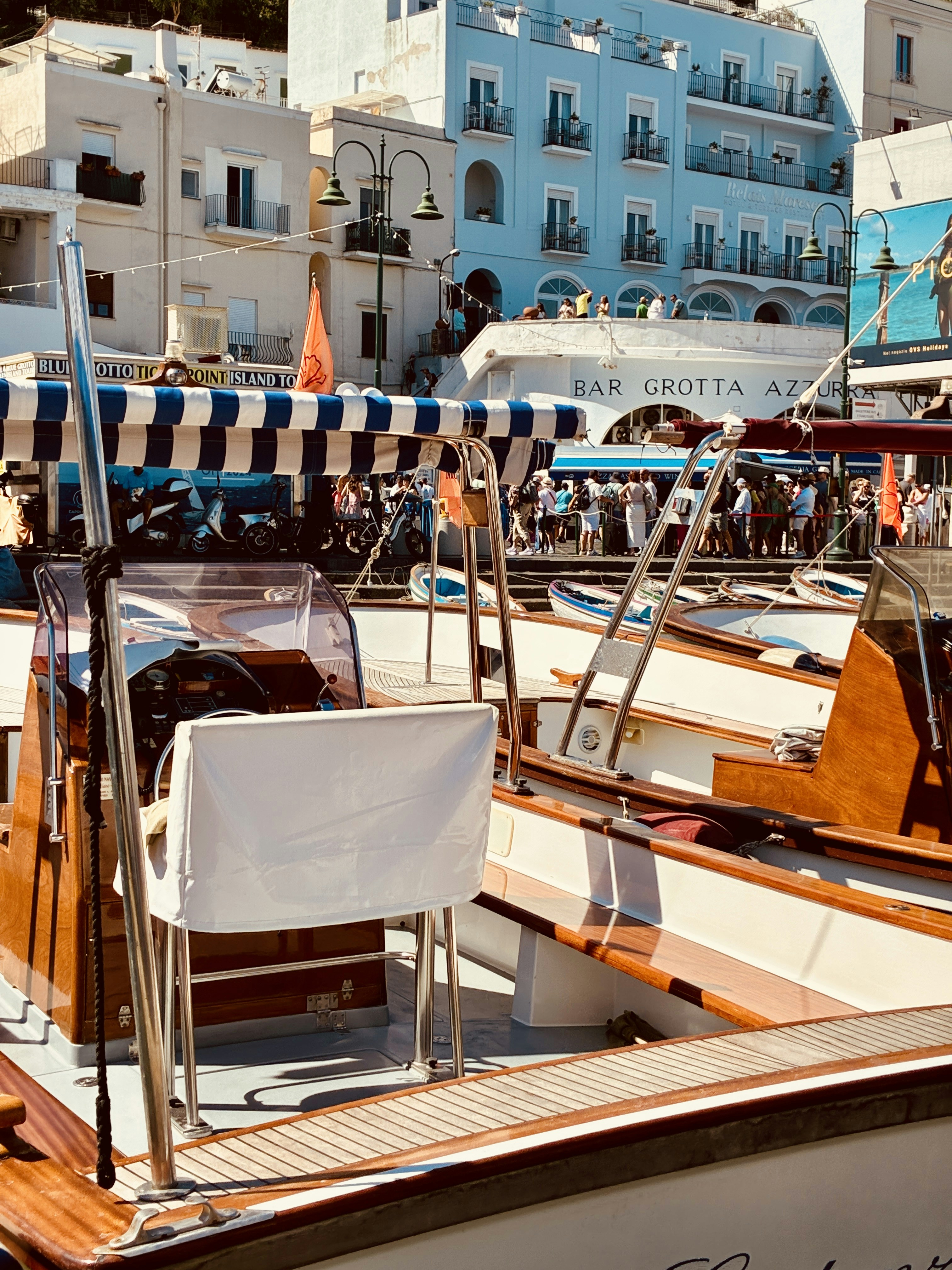 Wooden boats moored at a busy harbor in front of blue buildings