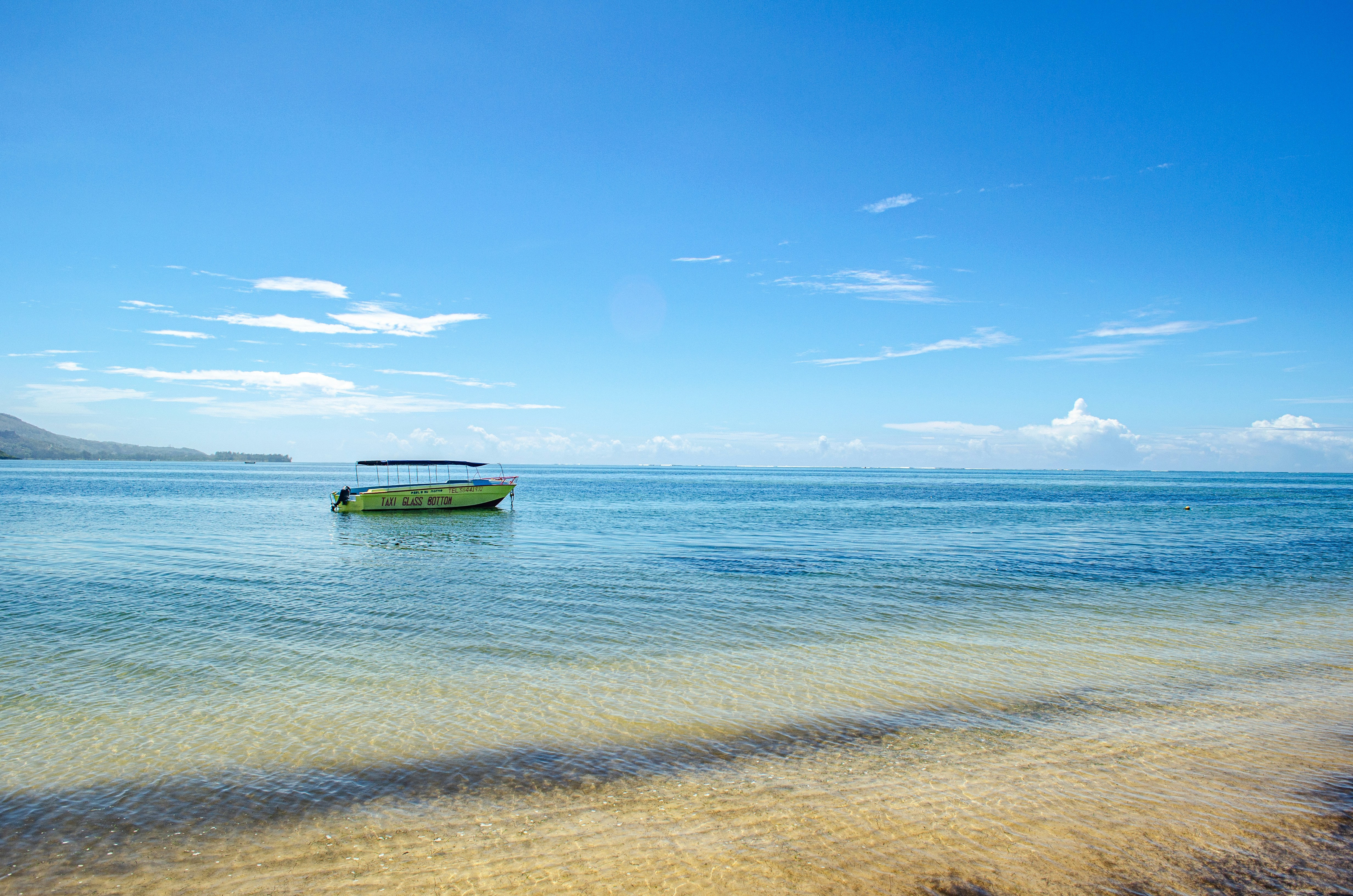 A yellow glass bottom boat floating on calm blue water under a clear sky