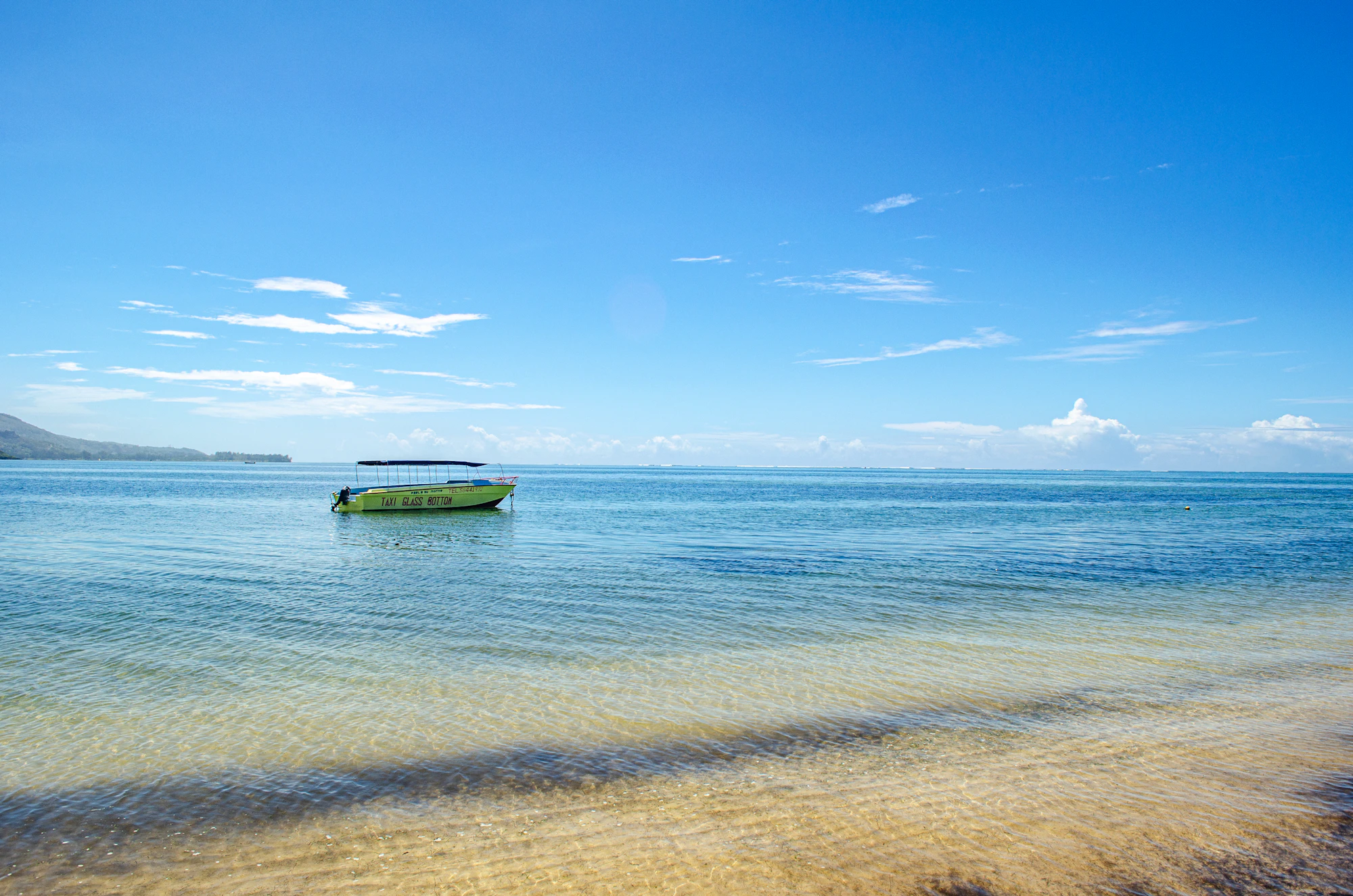 Small glass bottom boat floating on calm, clear turquoise water