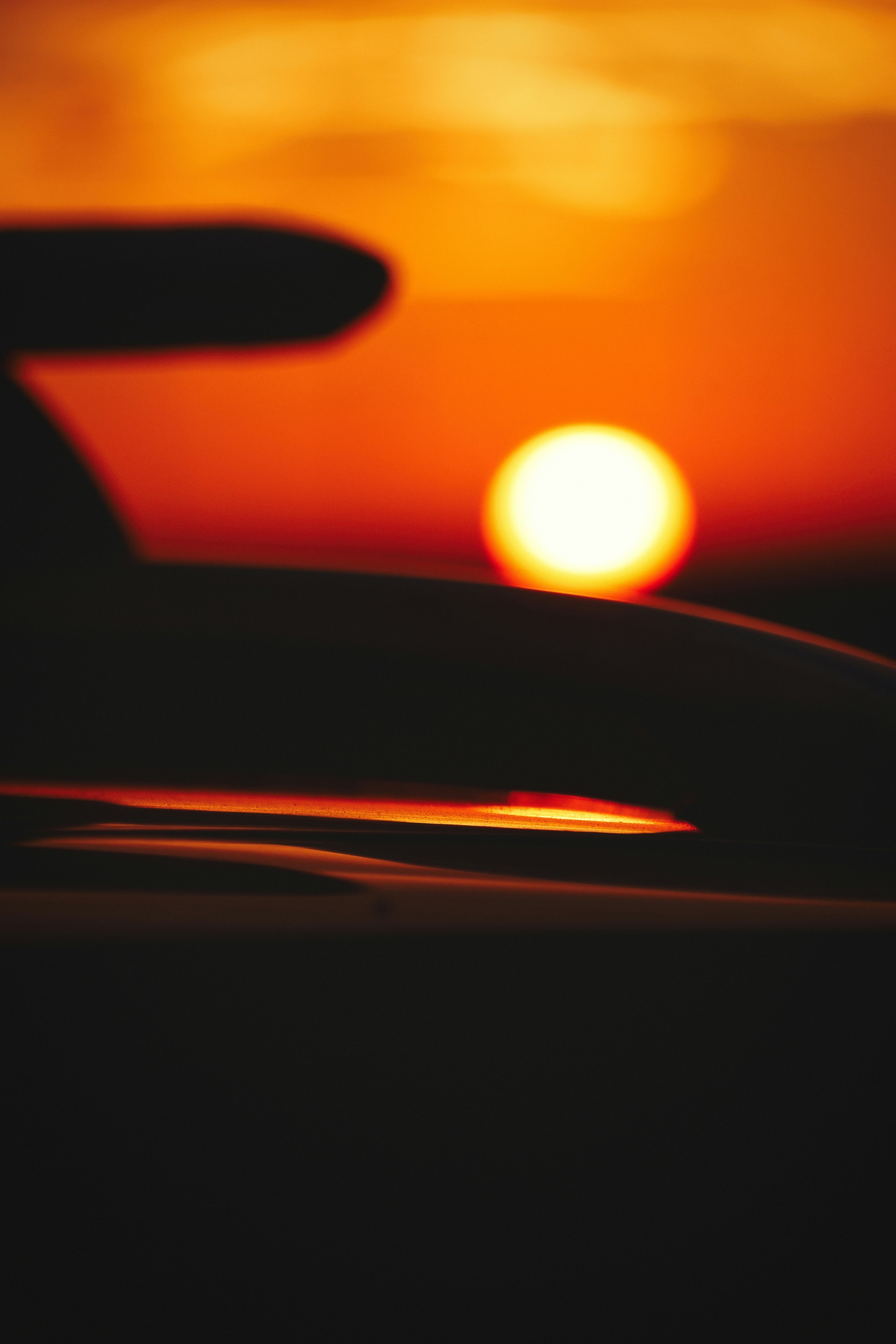 A low sun glowing behind the silhouette of a car spoiler