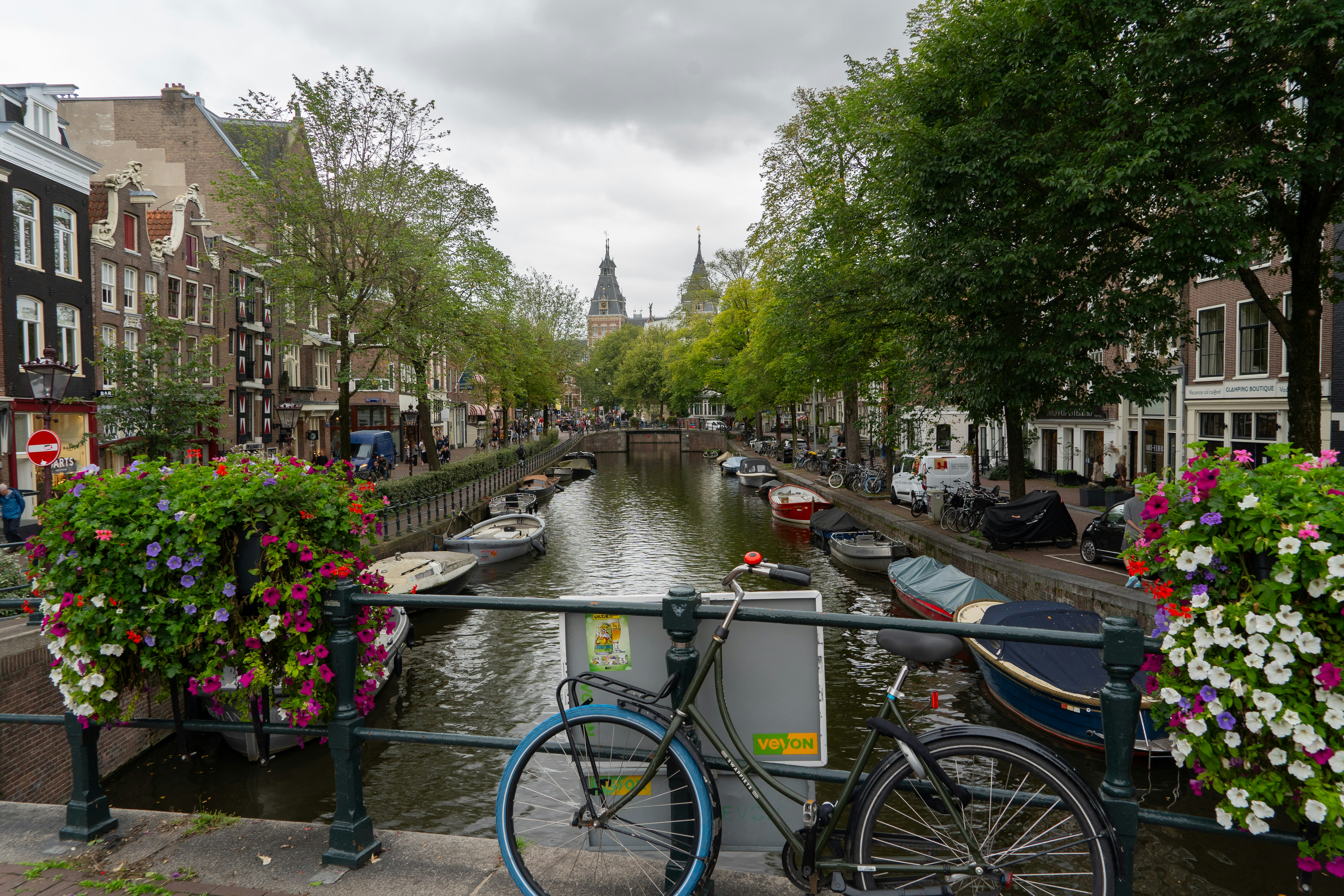 Ein Fahrrad, das auf einer Brücke über einen Kanal in Amsterdam mit Blumenkörben geparkt ist