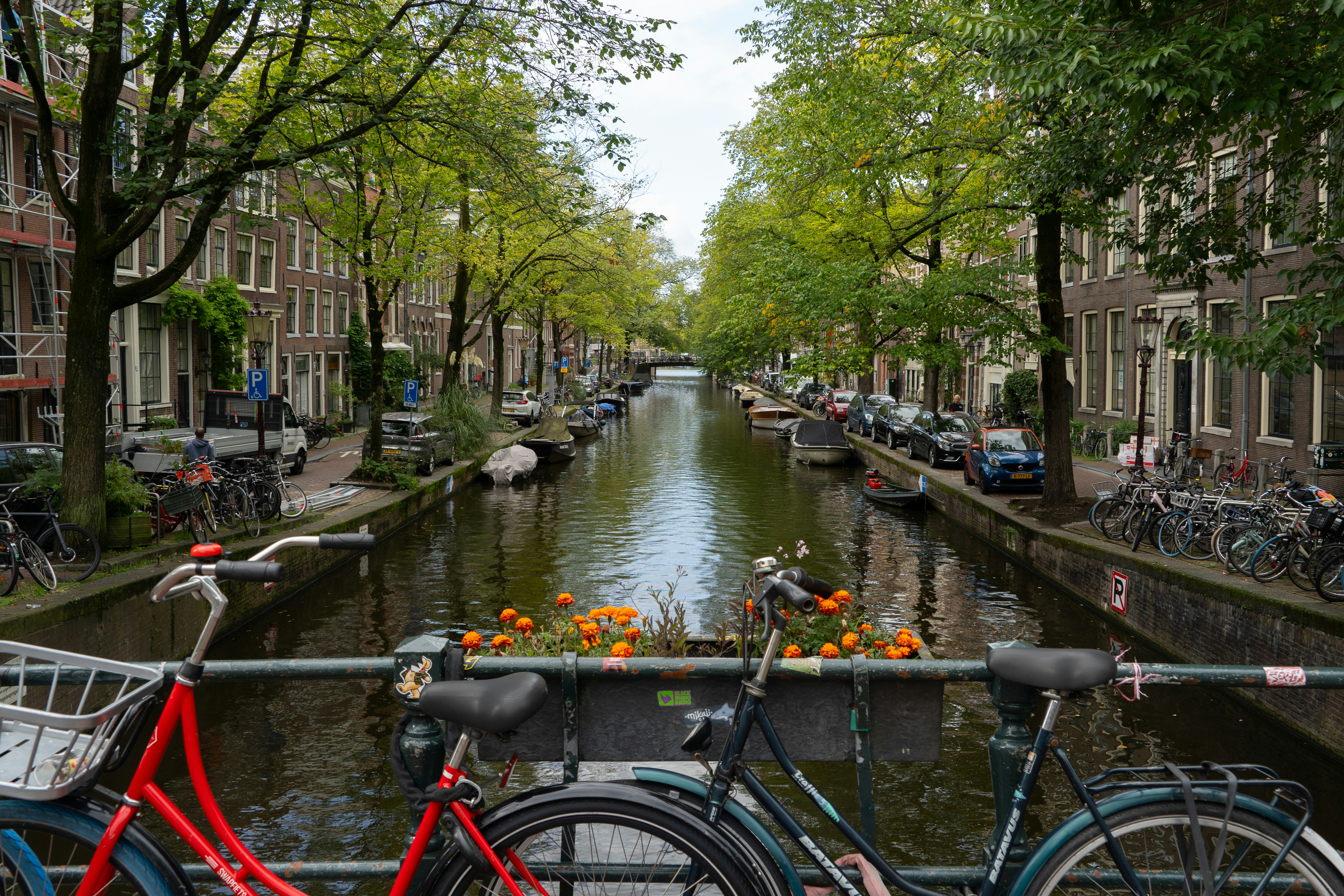 Zwei Fahrräder, die auf einer Brücke über einen Kanal in Amsterdam mit Bäumen geparkt sind