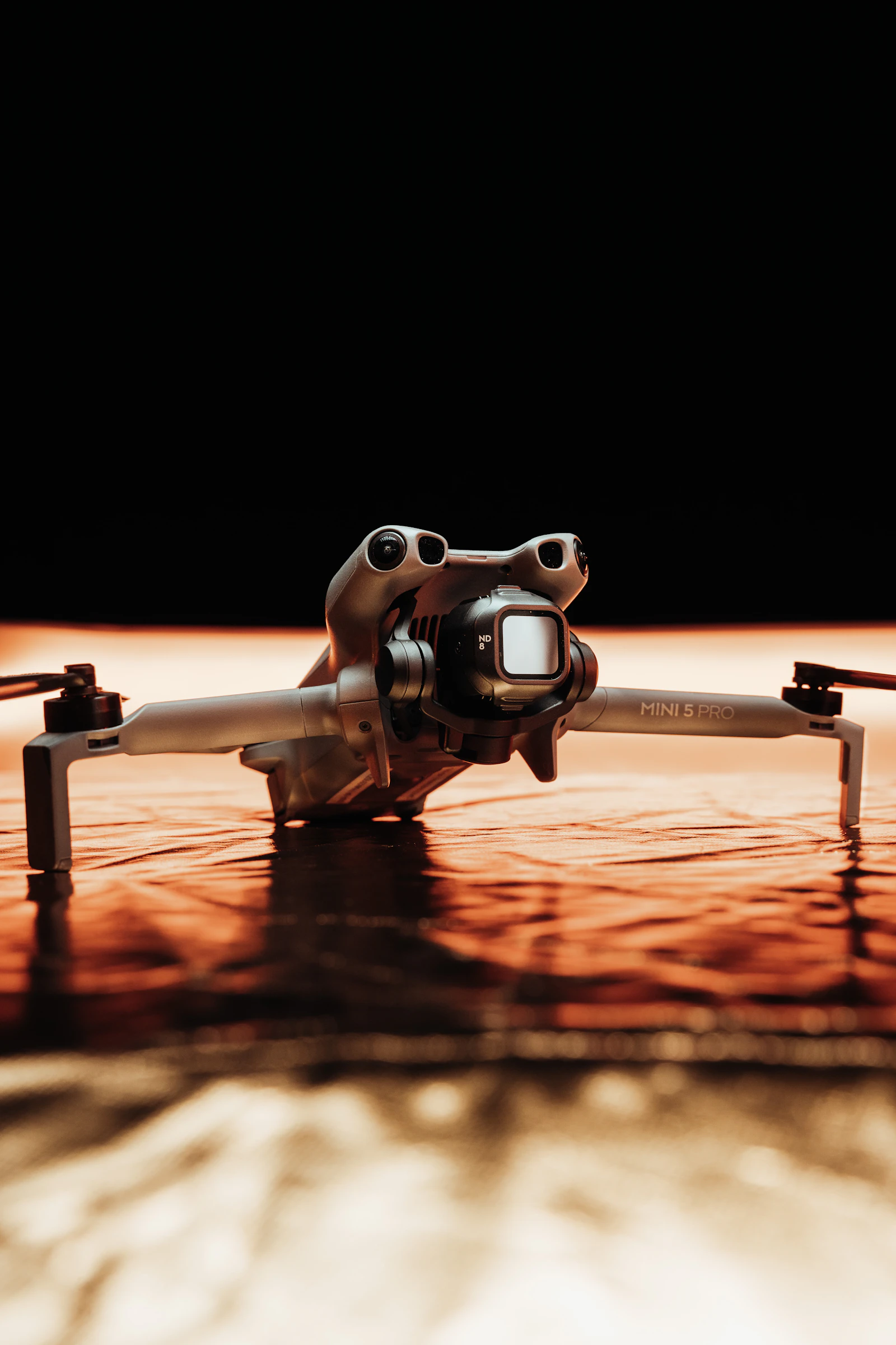 A DJI Mini 5 Pro drone on a glossy orange surface