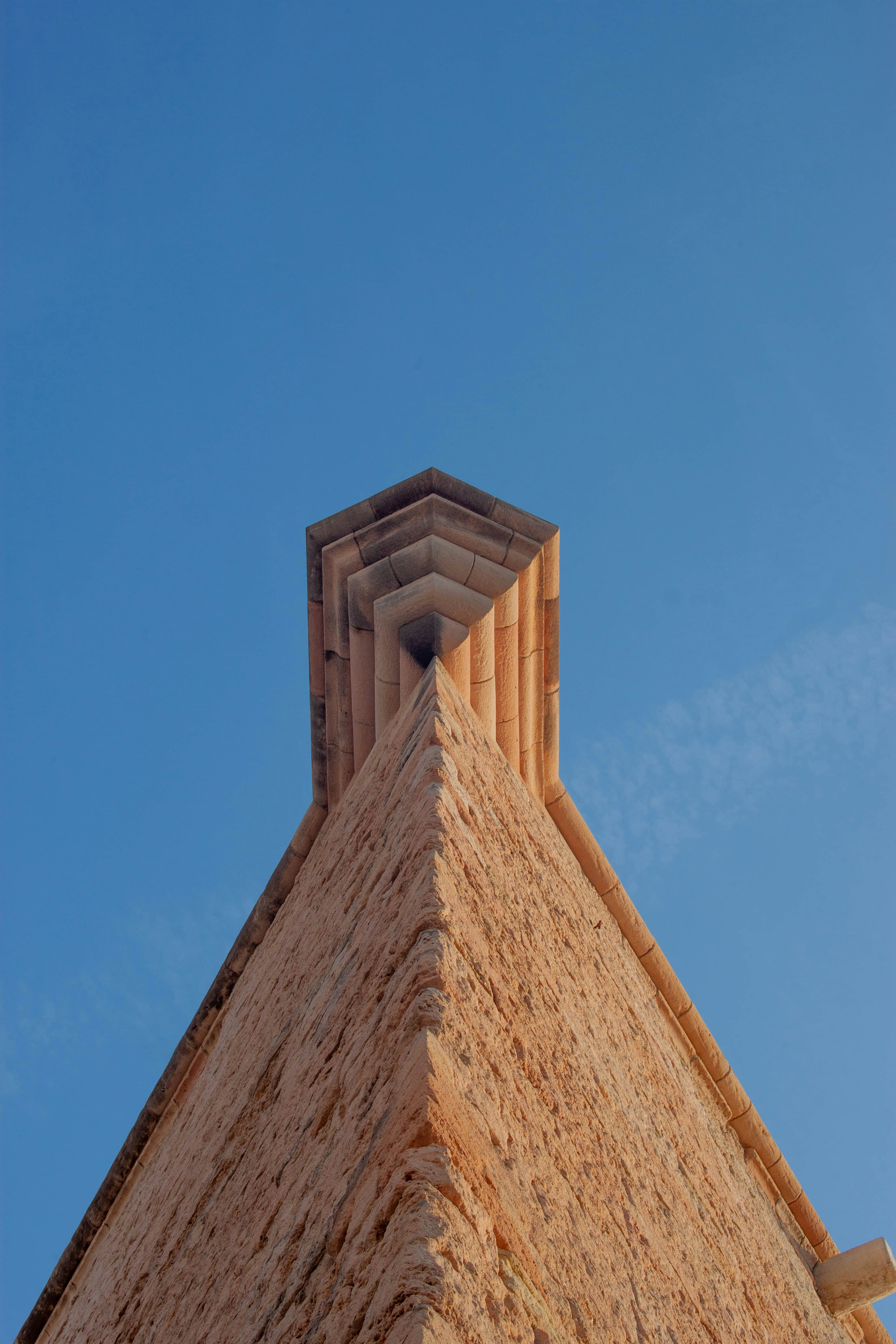 The sharp corner of a stone building against a clear blue sky