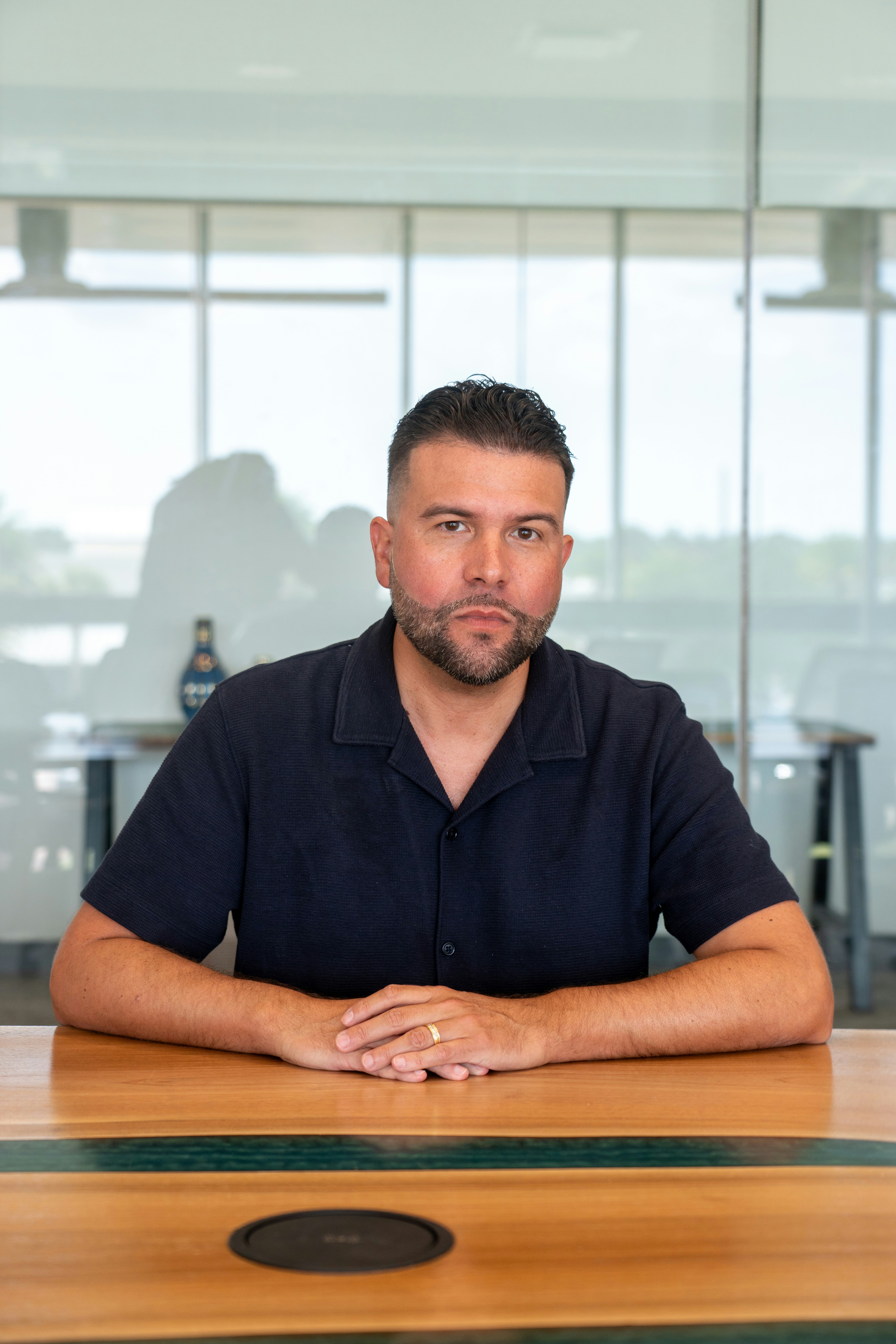 A man with a beard in a navy shirt at a wooden table