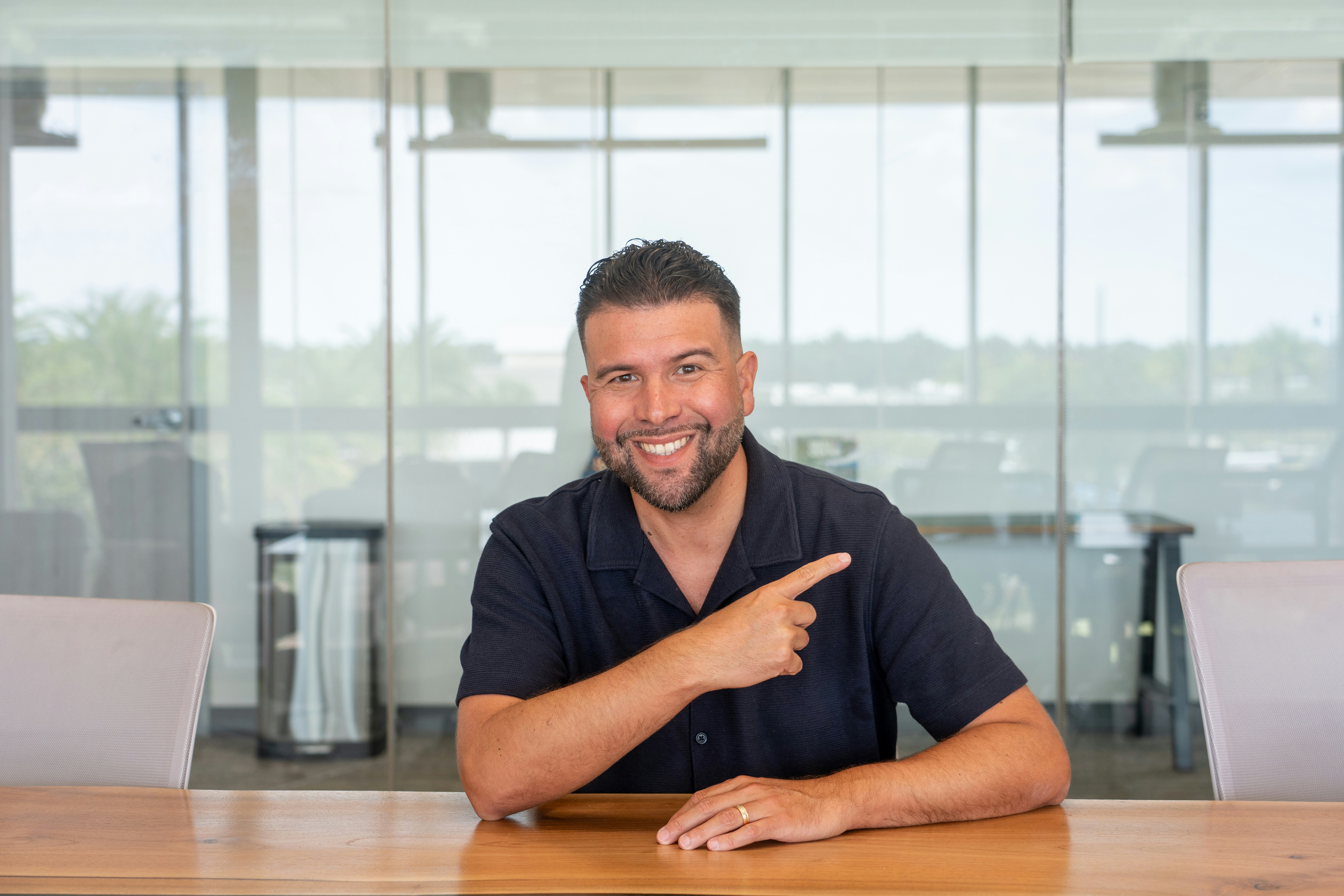 Un uomo con una polo blu navy che indica di lato in un ufficio moderno