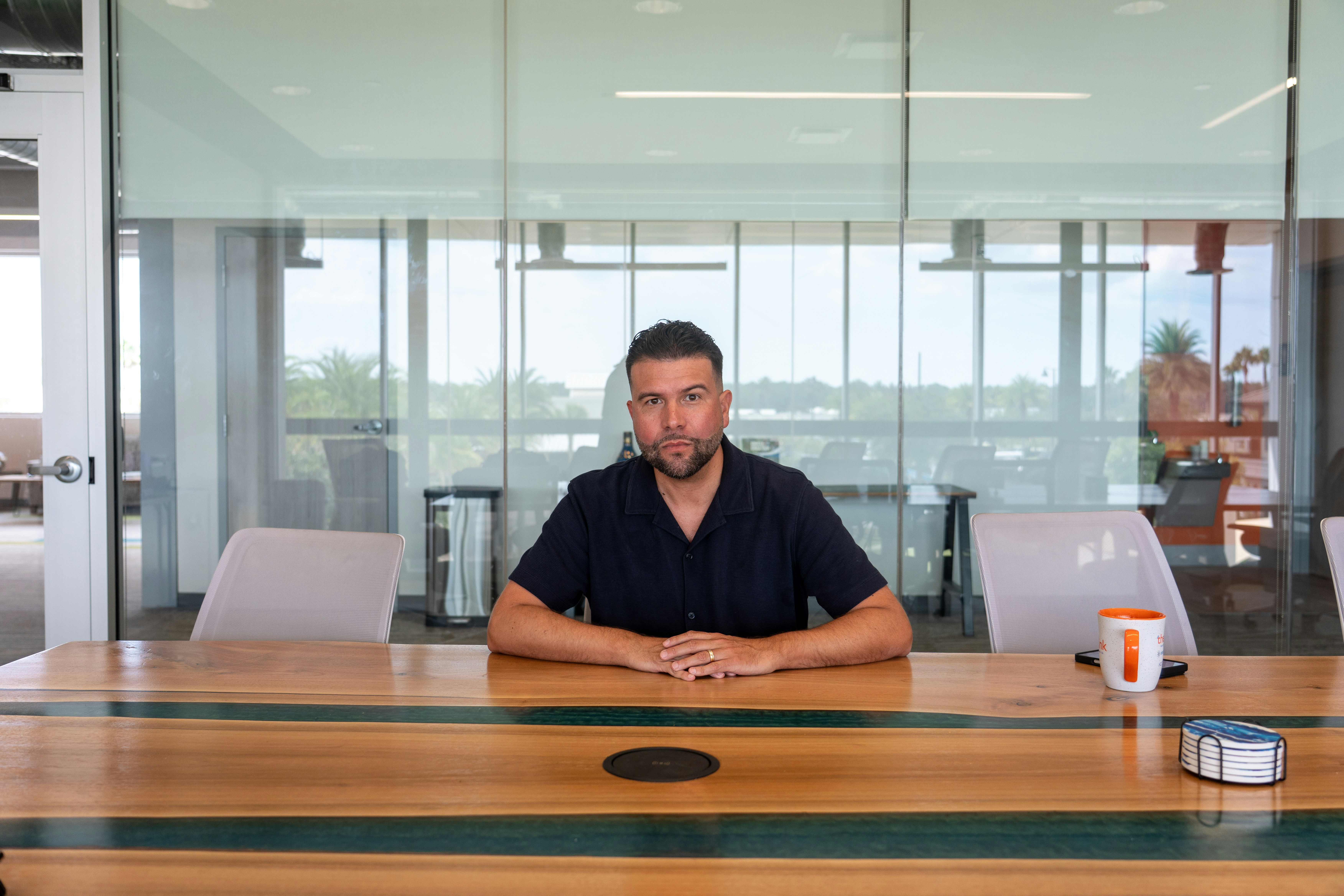 Business professional sitting alone at a large conference table in a modern office.