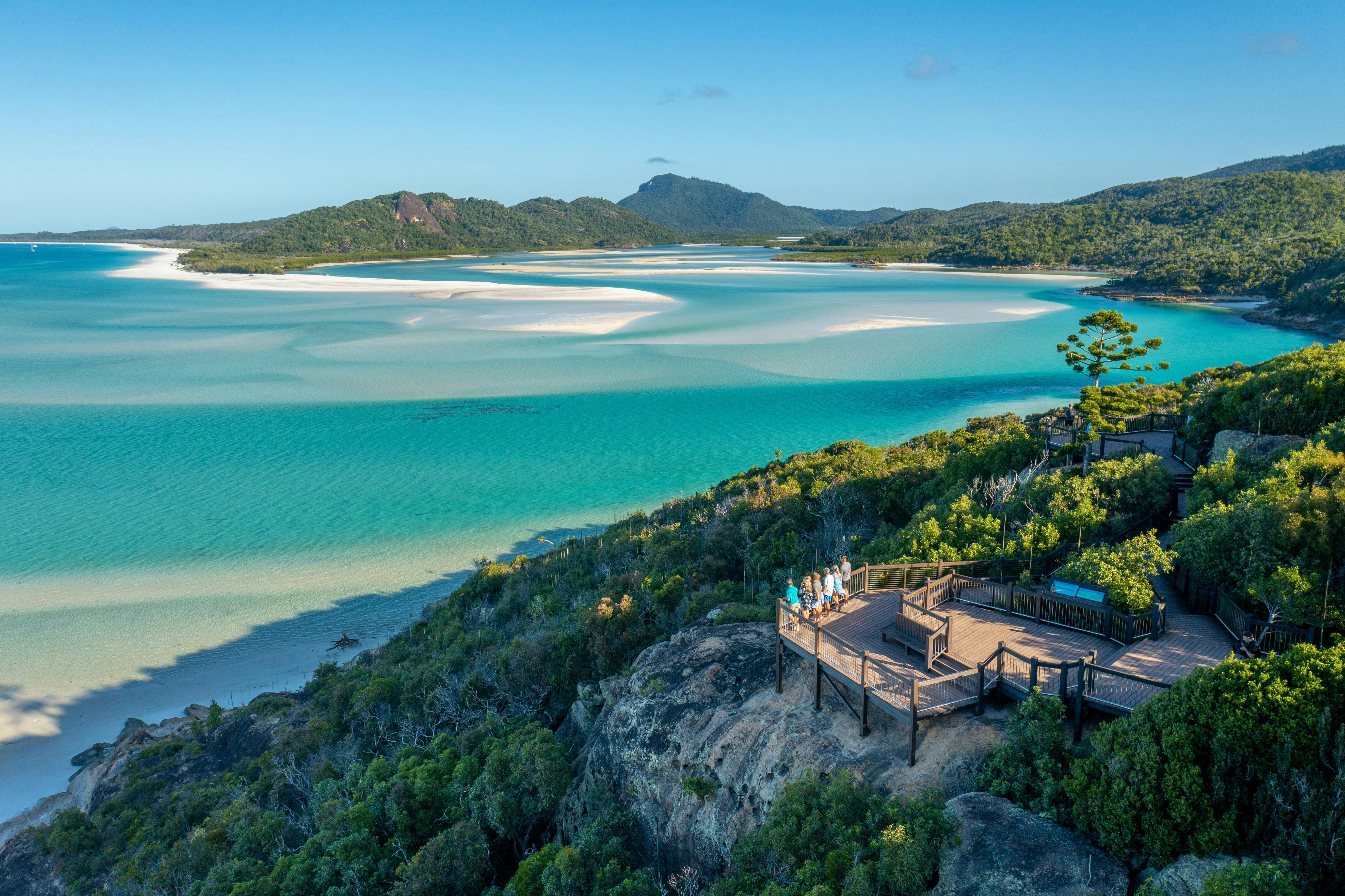 A group of people on a wooden observation deck overlooking Whitehaven Beach in Australia