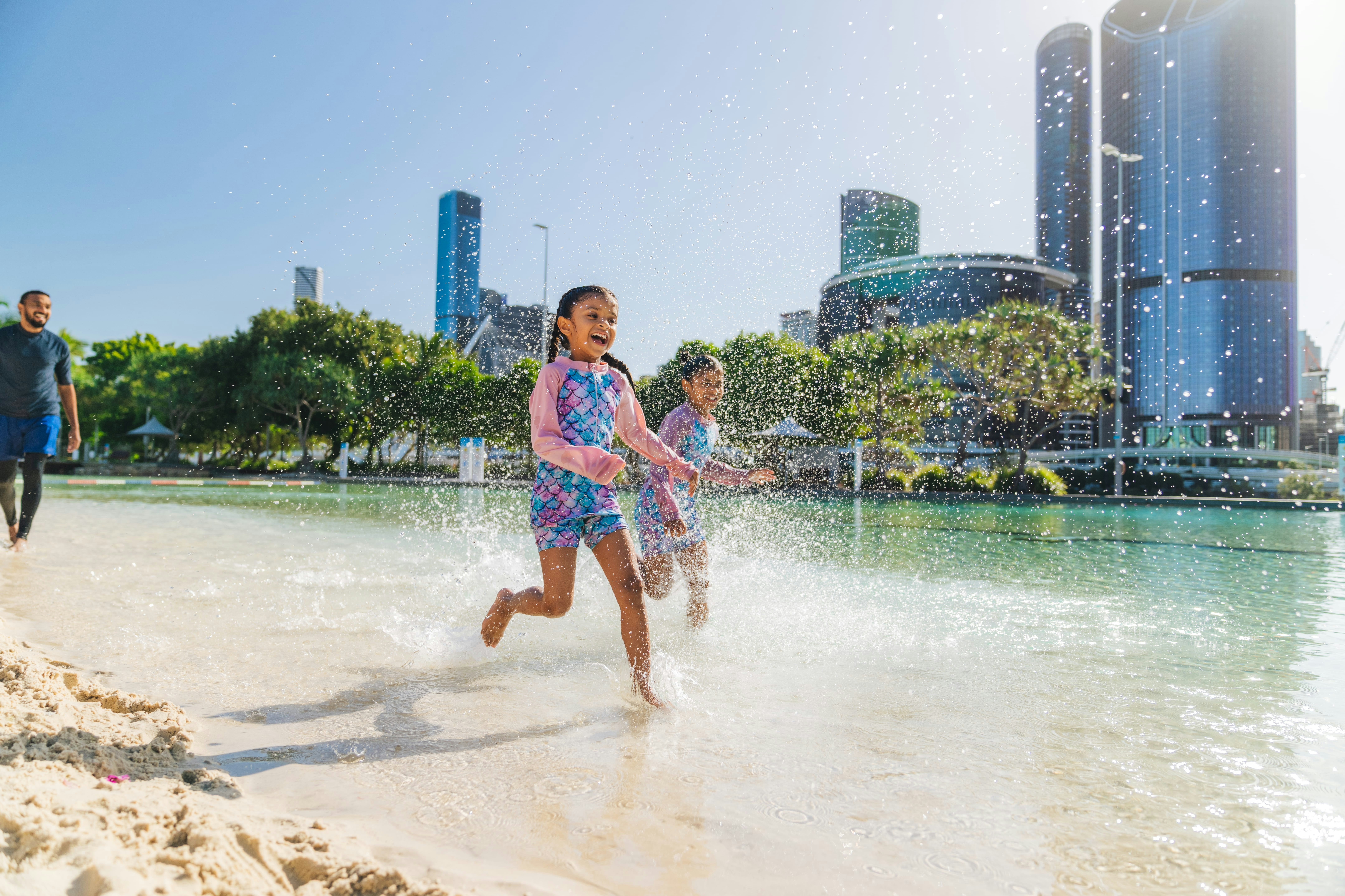 Man-made beach and lagoon on the edge of the Brisbane River with city backdrop