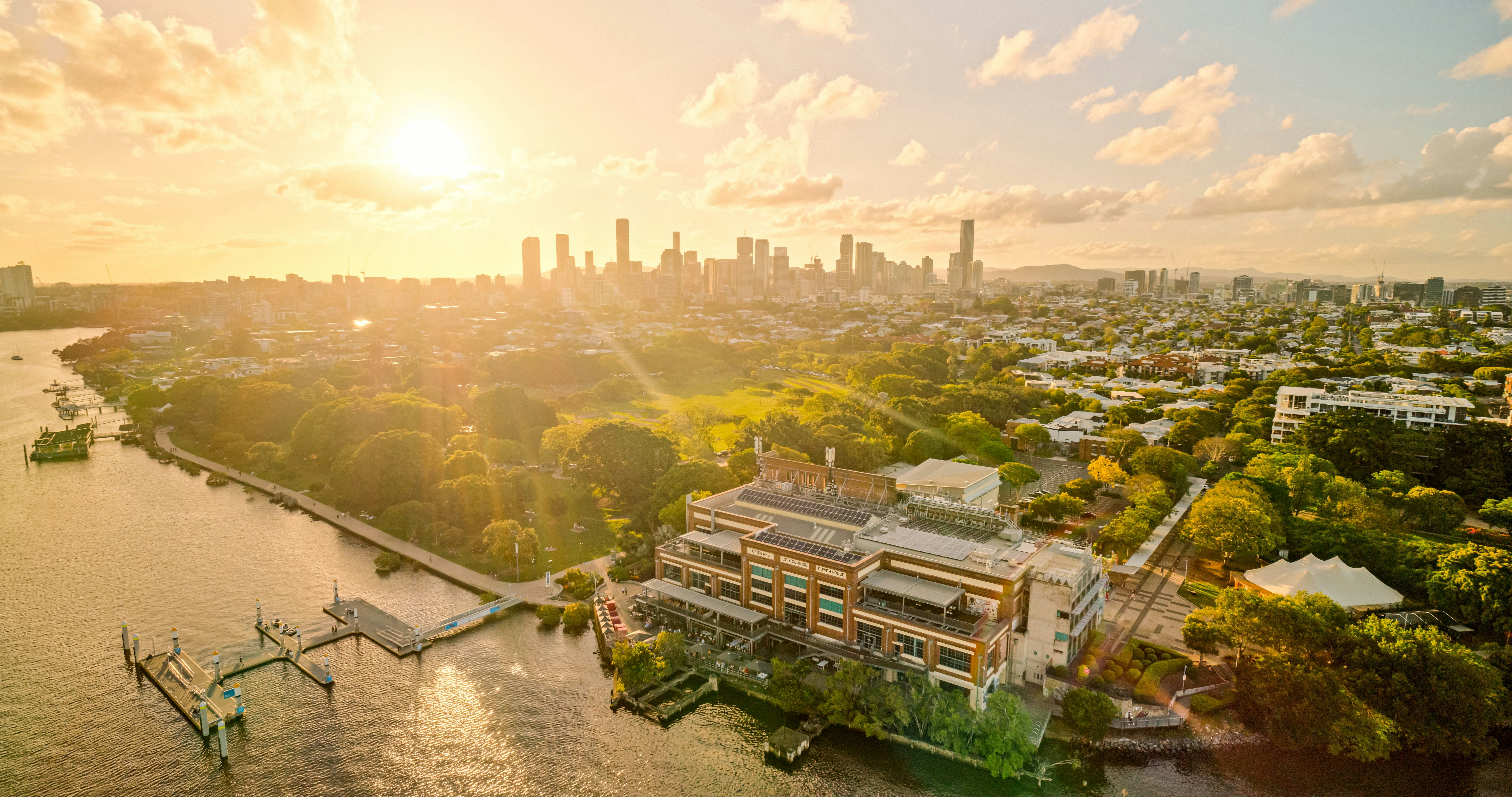 Aerial view of the Brisbane Powerhouse on the riverbank at golden hour