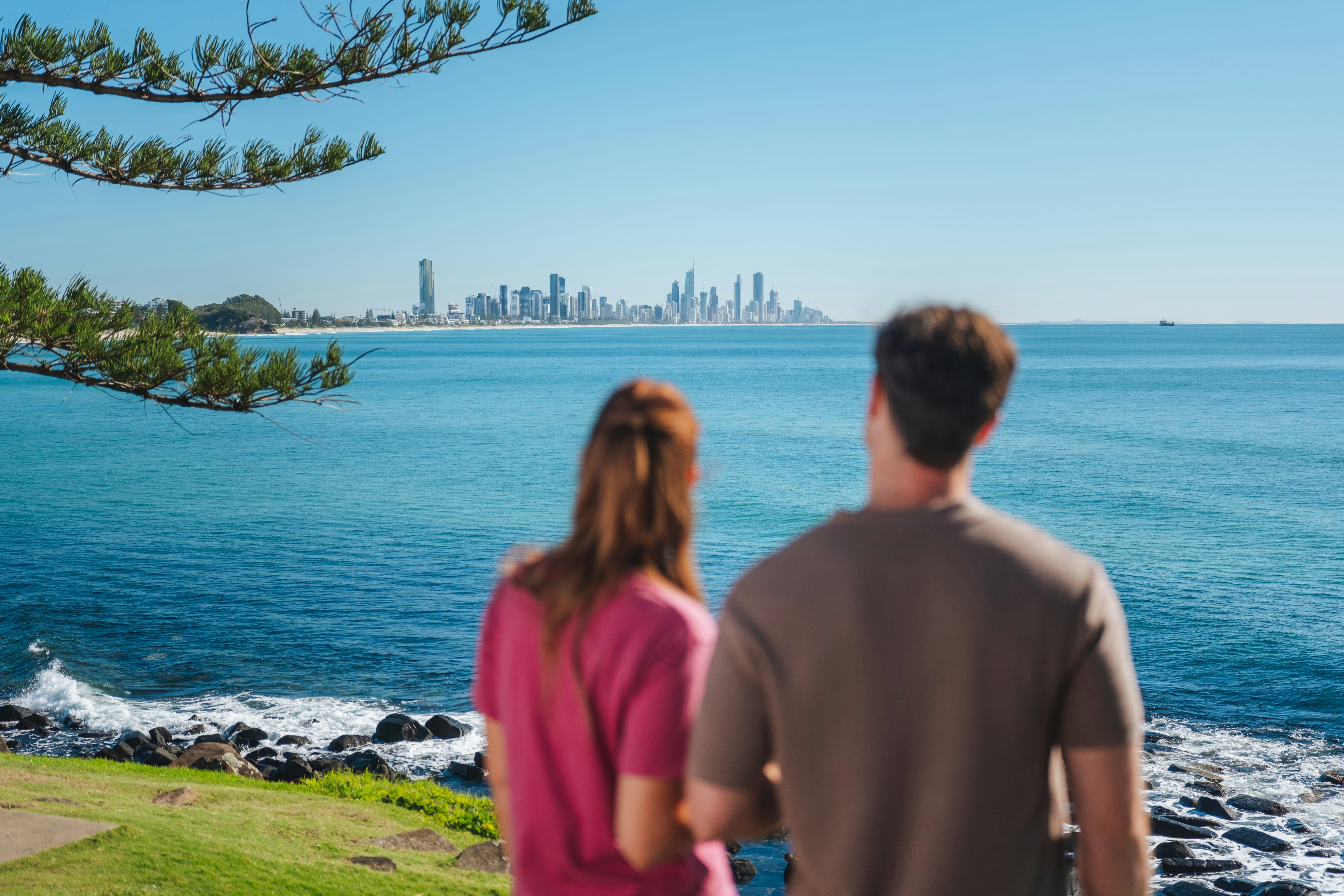 Two people looking at the Gold Coast skyline across the blue ocean