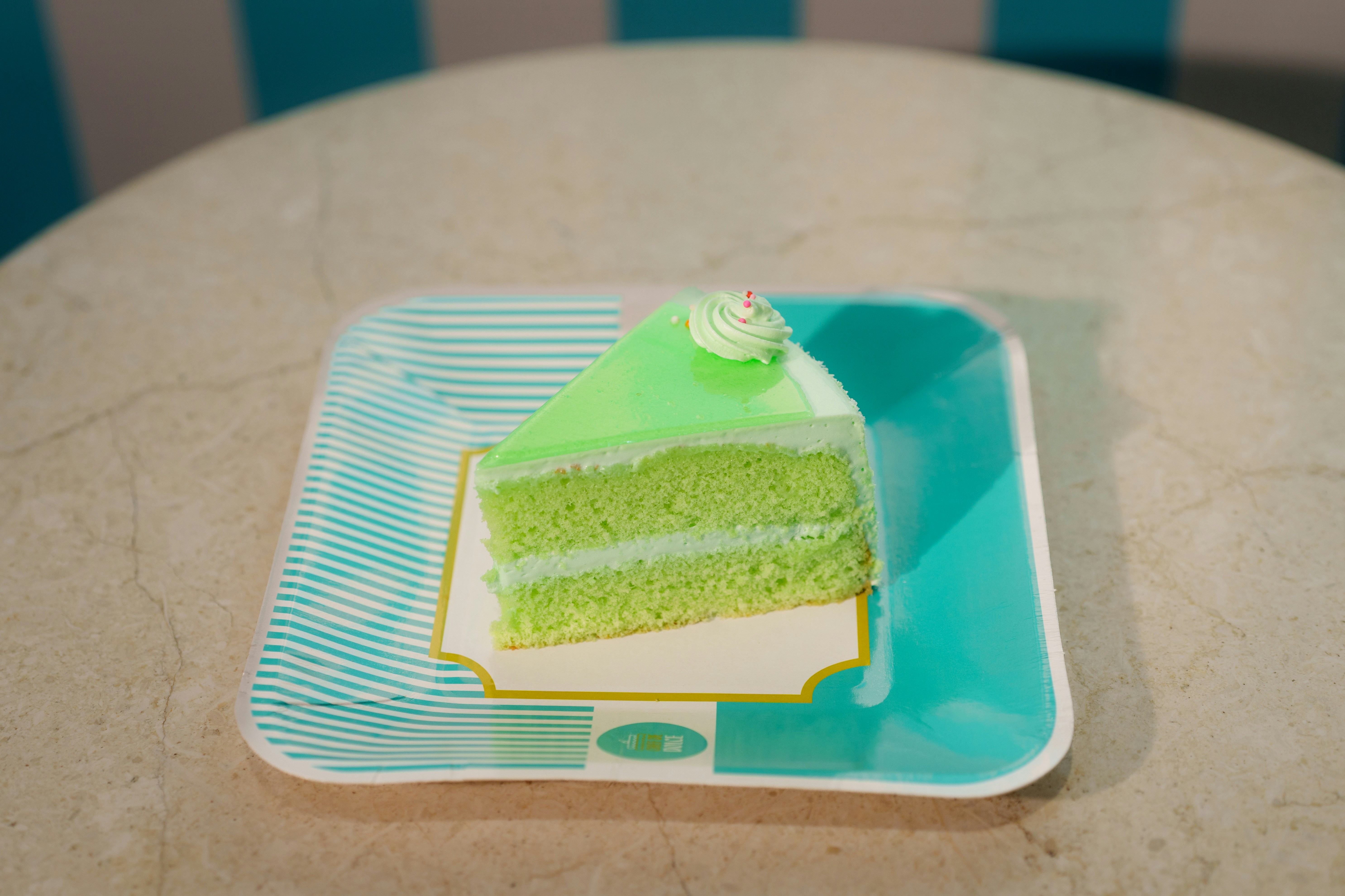 Slice of green layered cake on a striped plate