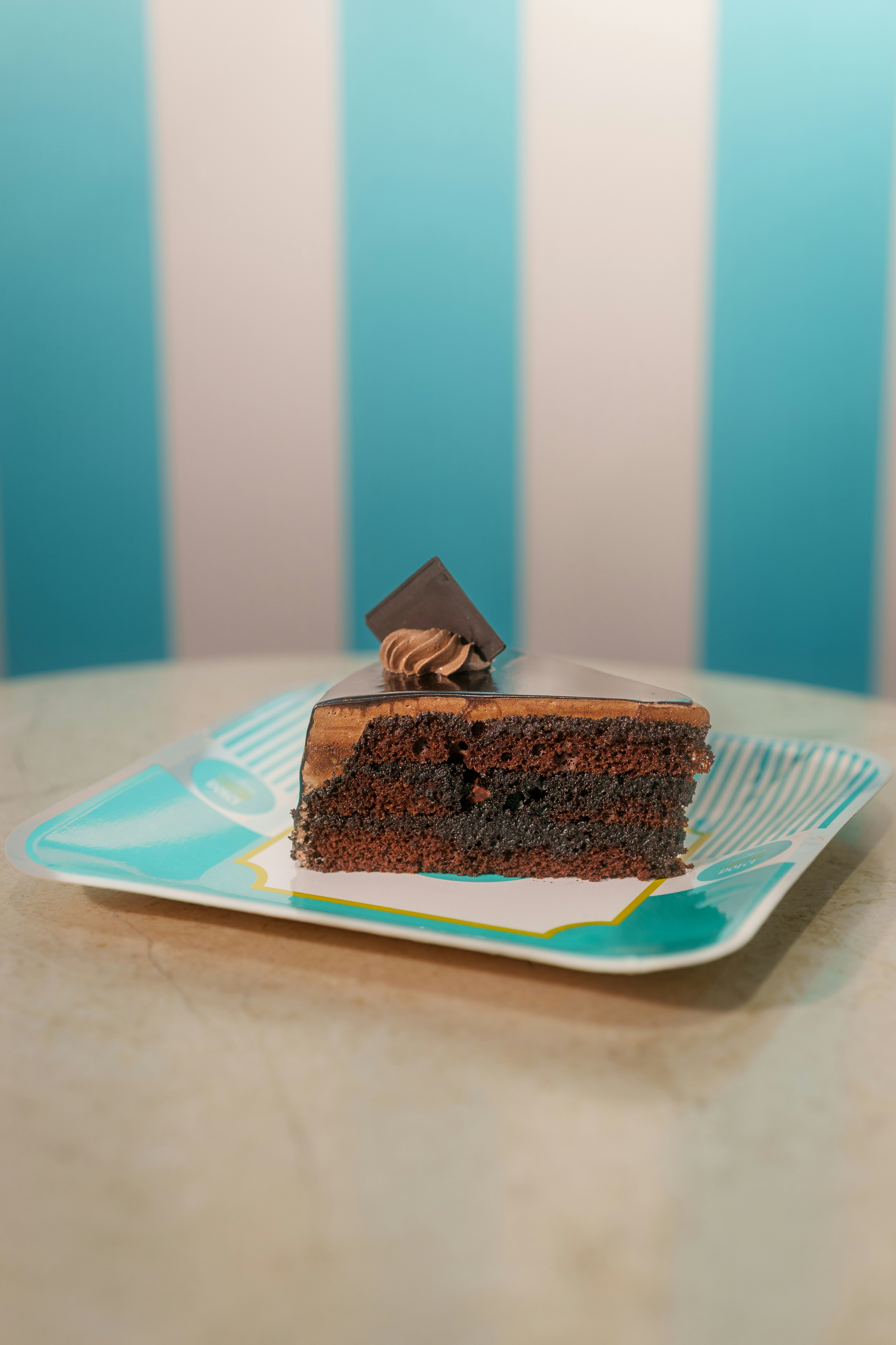 A slice of chocolate cake on a turquoise patterned plate