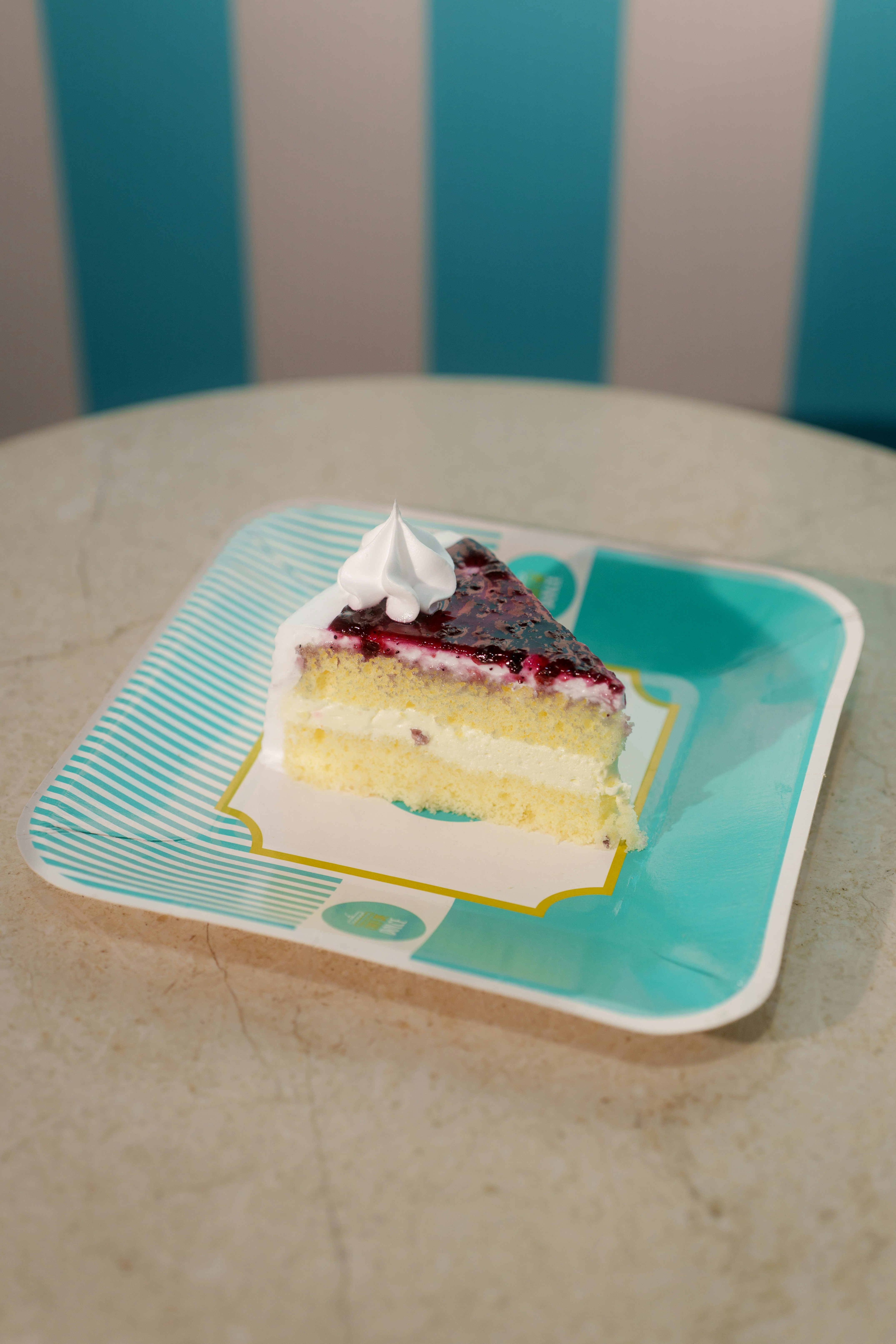 A slice of sponge cake with berry topping on a paper plate