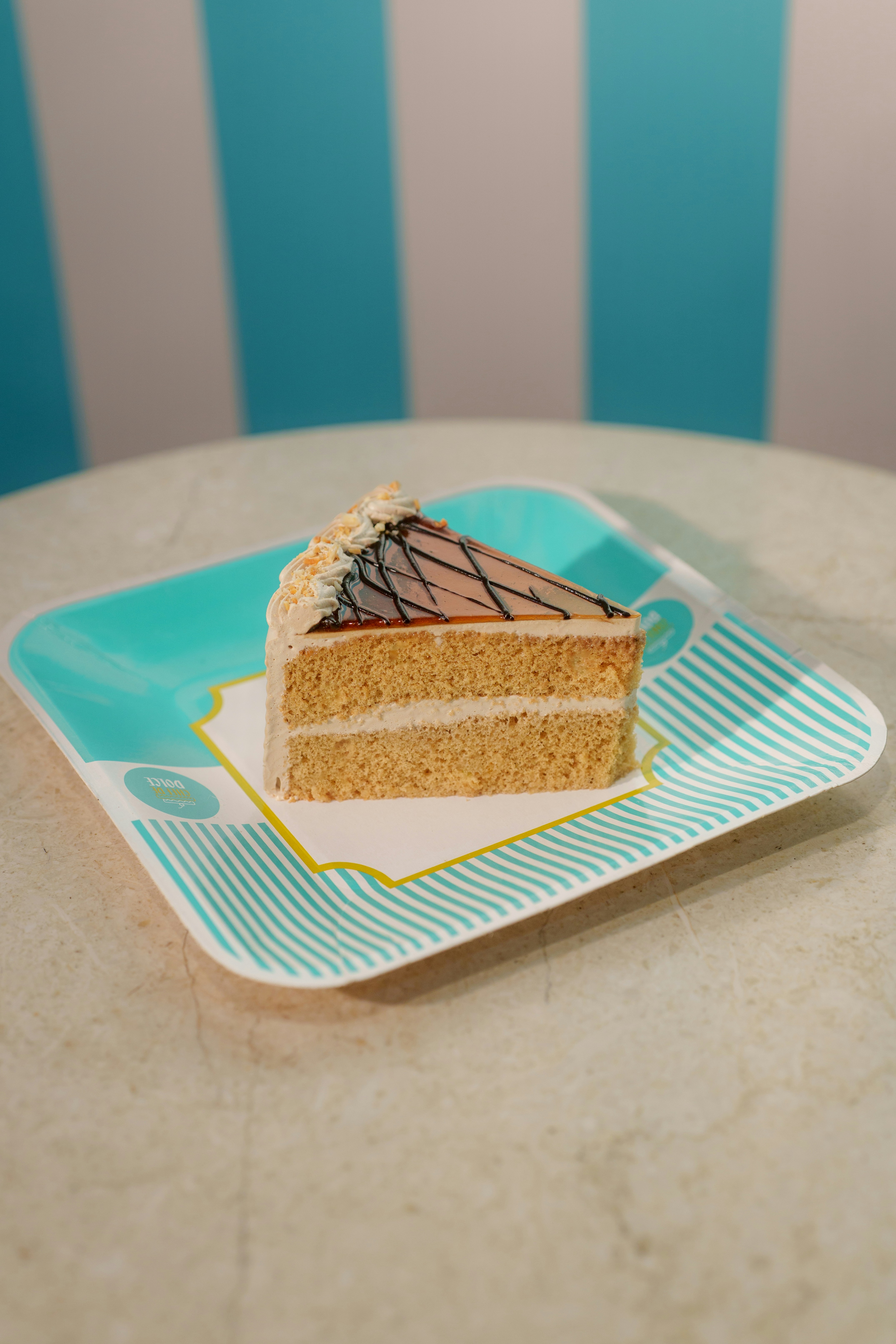 A slice of sponge cake with caramel topping on a patterned turquoise plate